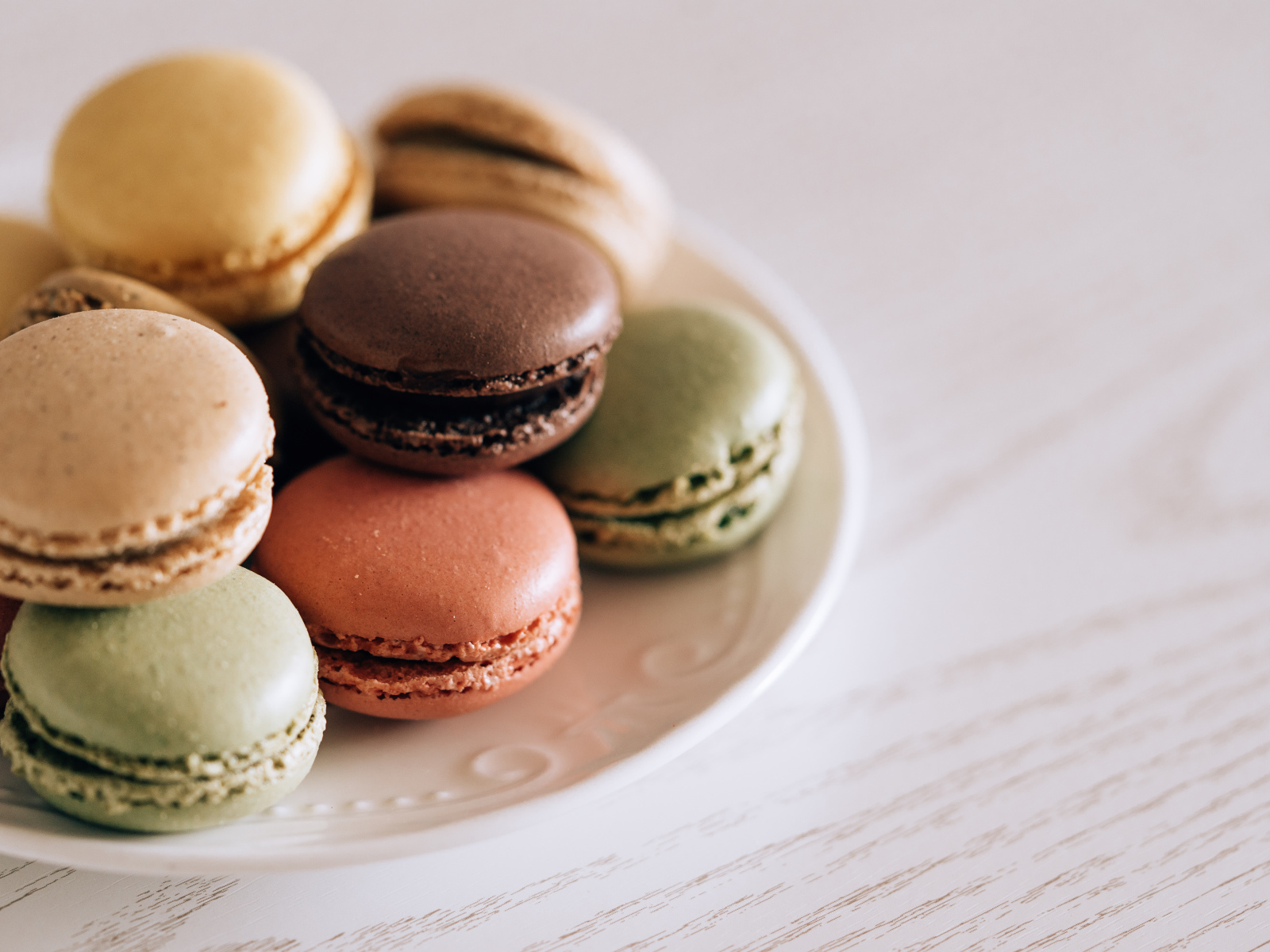 Разноцветный свежий десерт макарон на большой тарелке 