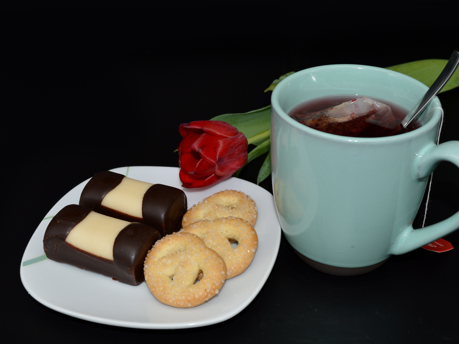 Печенье с конфетами на столе с чашкой чая и тюльпаном