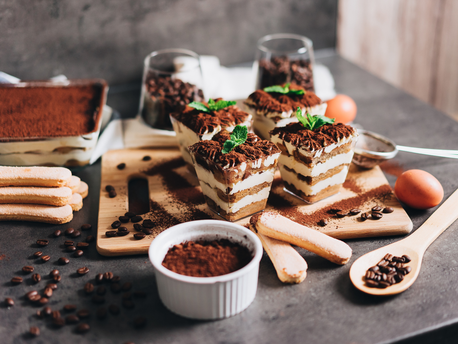 Аппетитный десерт тирамису в креманках на столе с кофейными зернами