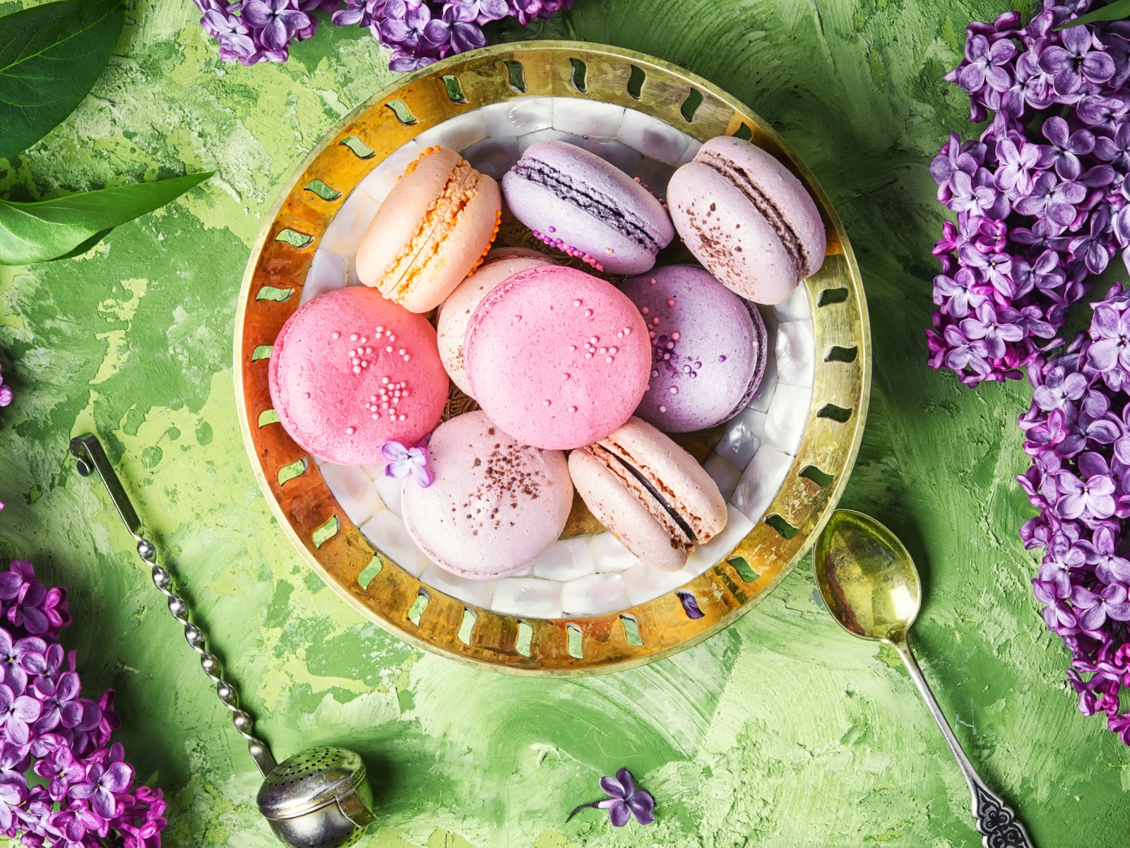 Разный десерт макарон на столе с цветами сирени 