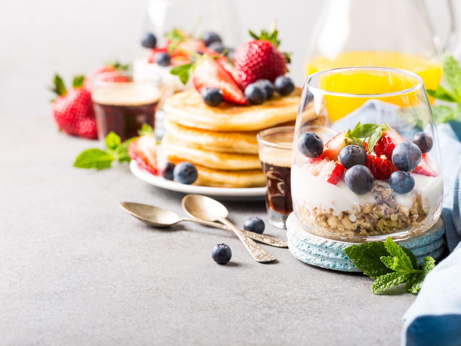 Оладьи на столе с ягодами, мюсли и кофе