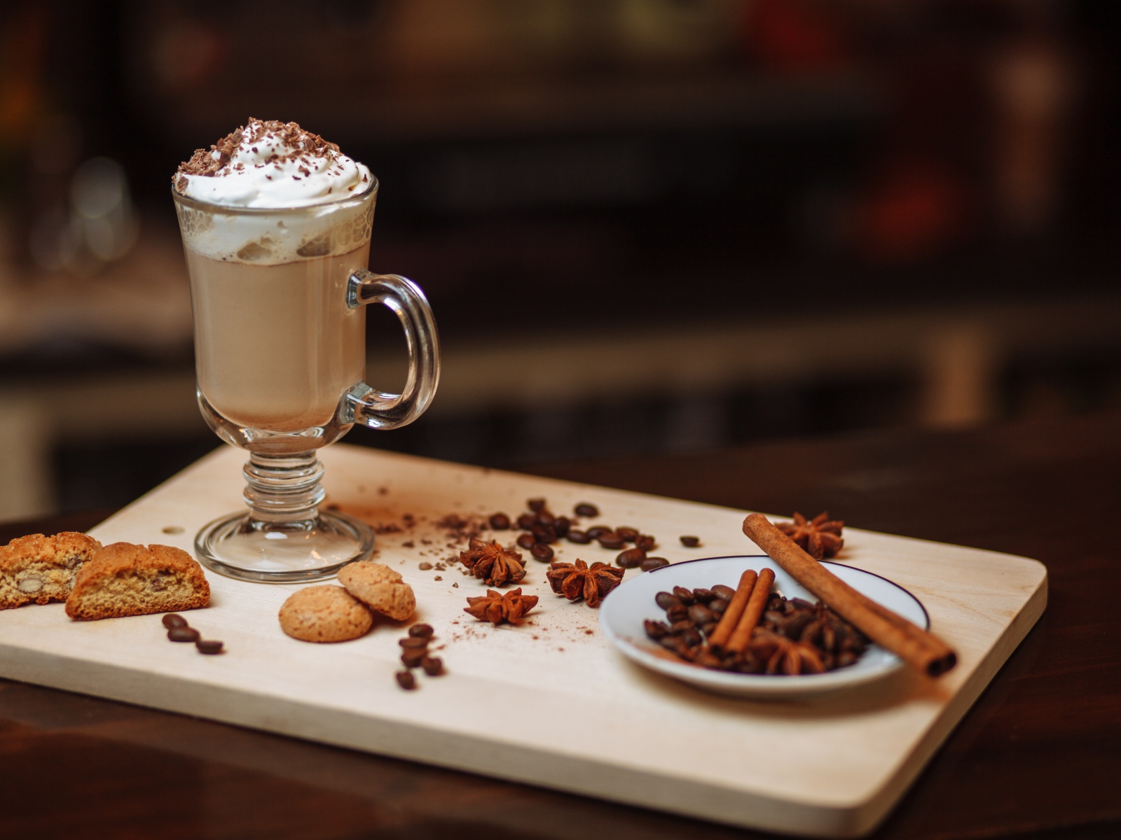 Горячее какао со сливками на столе с печеньем, зернами кофе и пряностями 