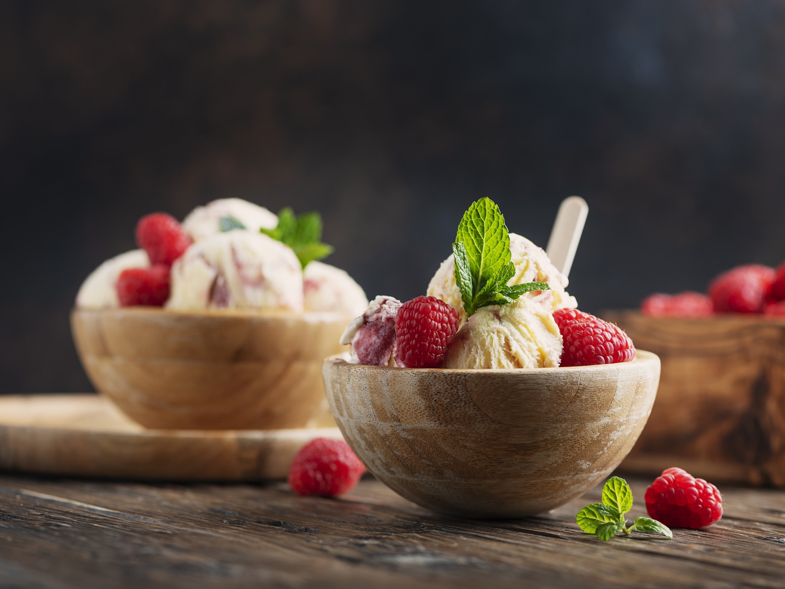 Шарики мороженого в деревянных мисках с ягодами малины