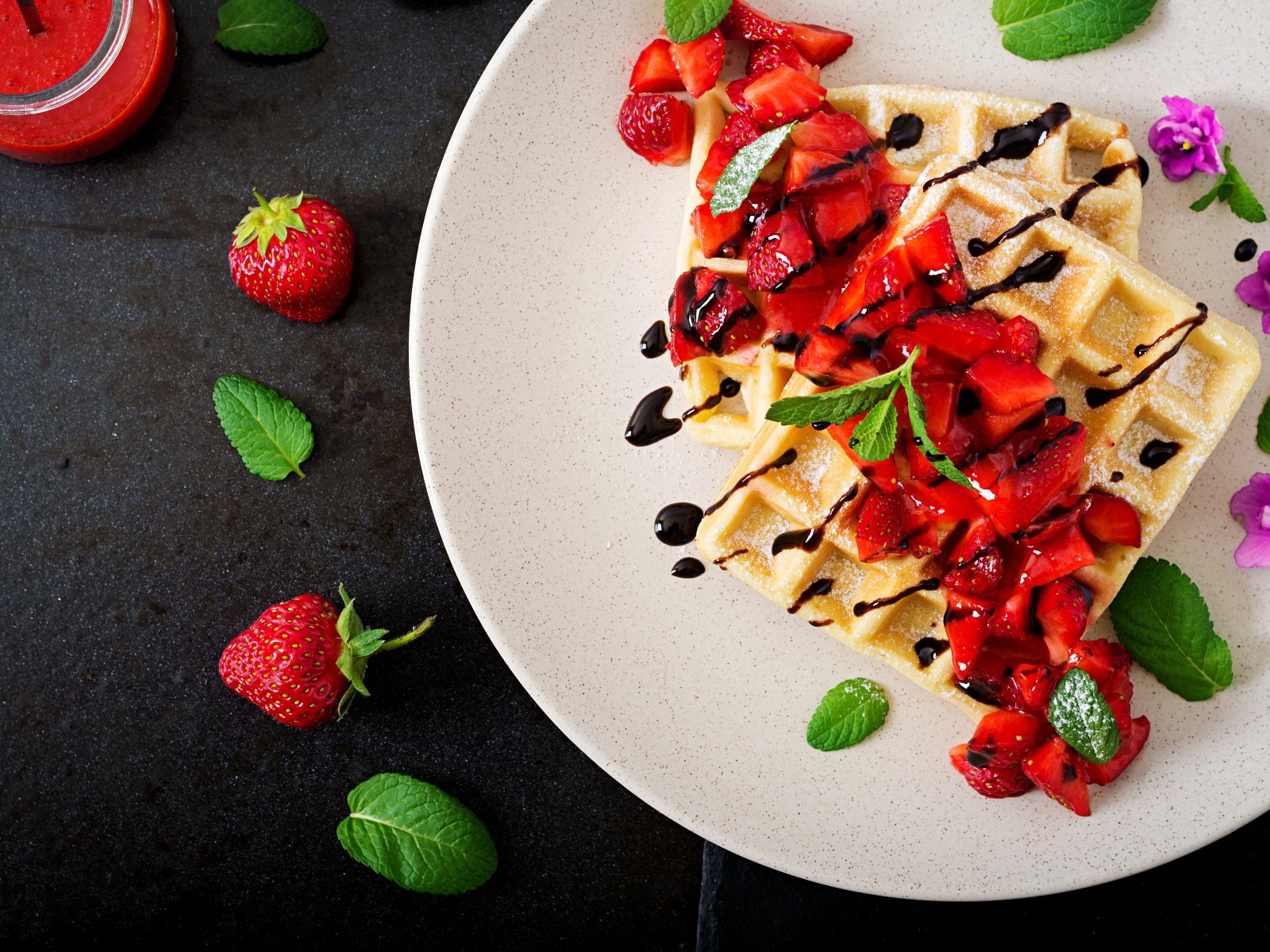 Large waffles with strawberries and chocolate on a white plate