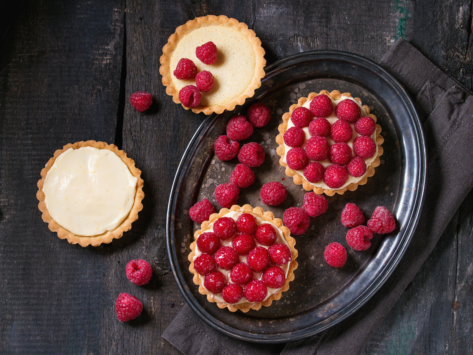 Кексы с кремом на блюде с малиной 