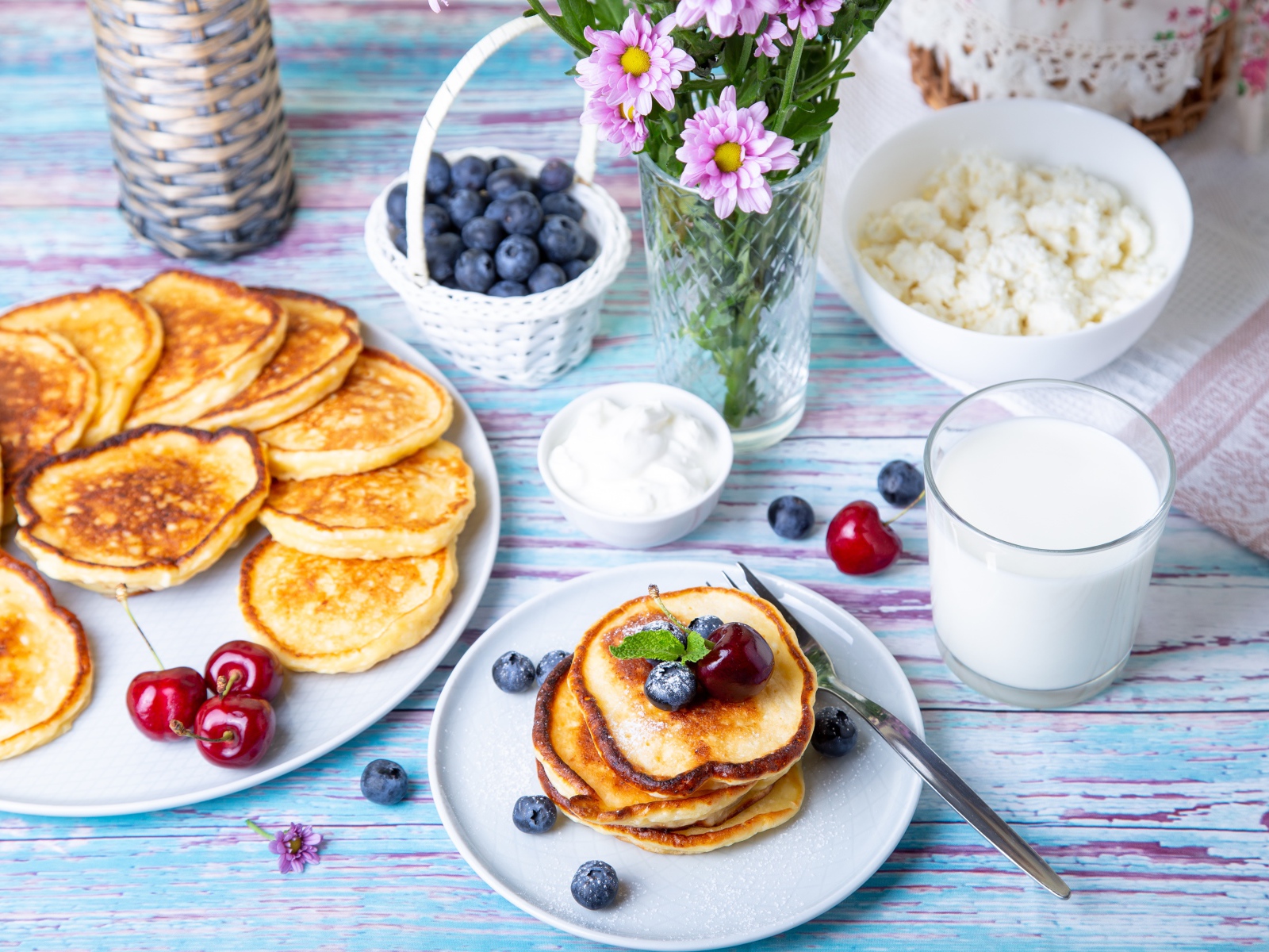 Вкусные оладьи на столе с ягодами черники, творогом и молоком