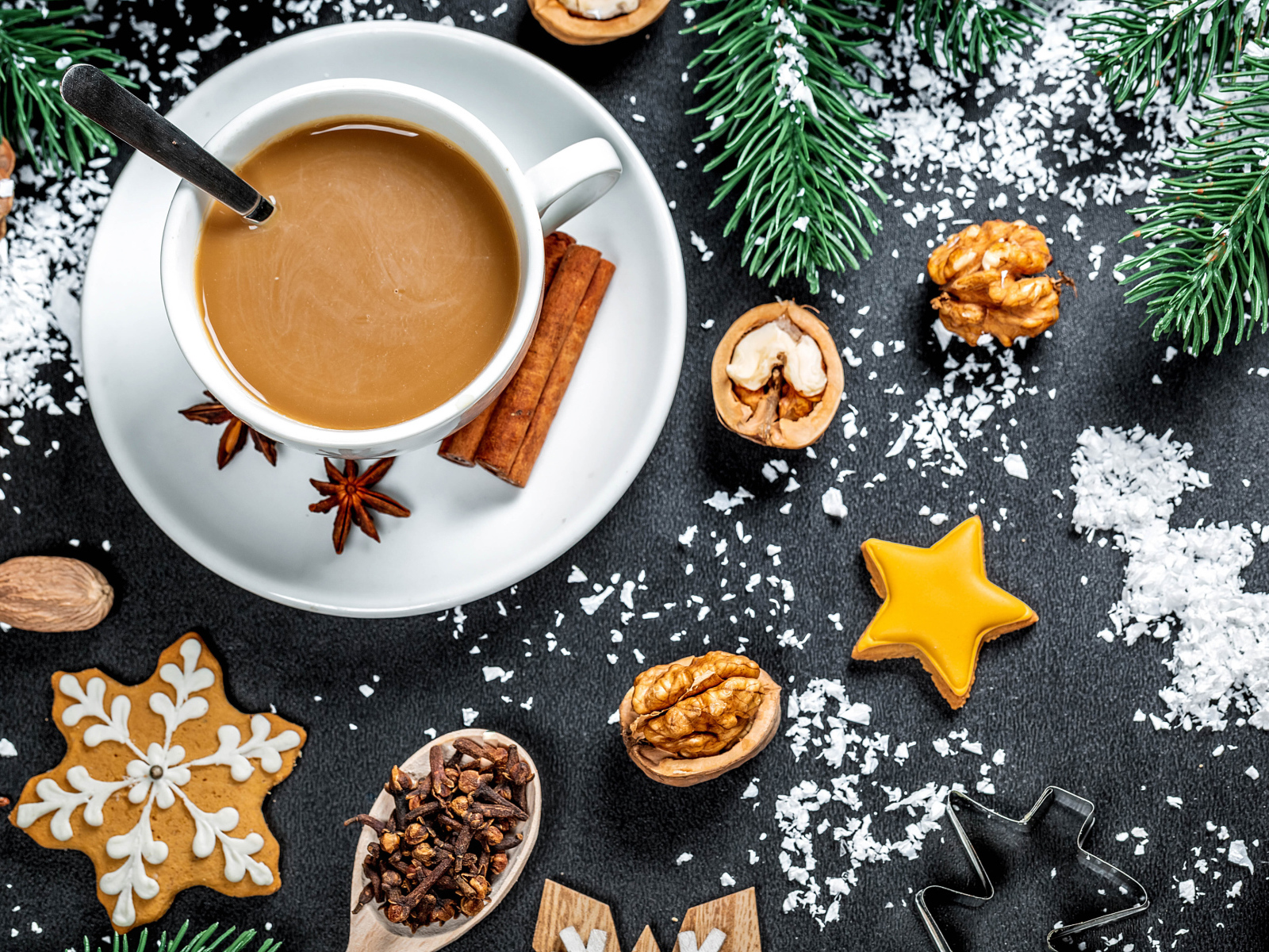 Чашка горячего кофе на столе с орехами и еловыми ветками 