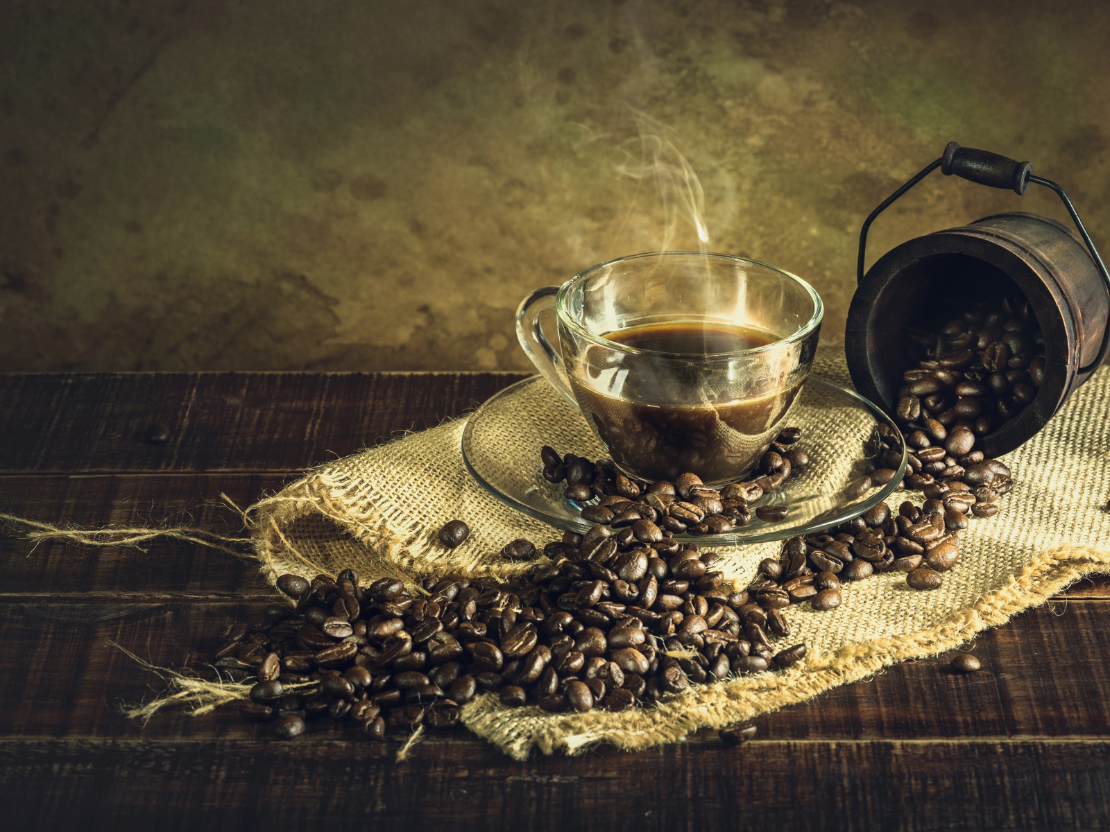 Чашка горячего крепкого кофе на столе с зернами