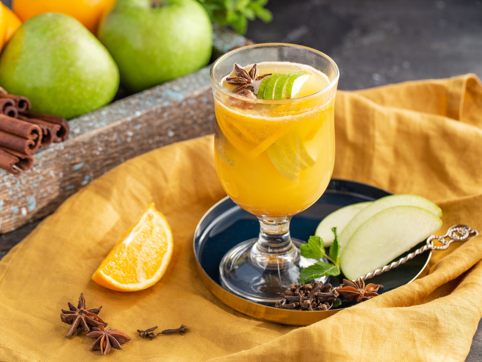 Стакан лимонада на столе с яблоками и корицей 