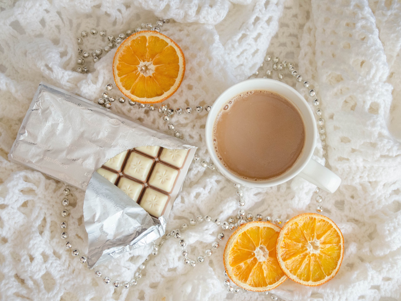Чашка какао, шоколад и апельсин на белом пледе