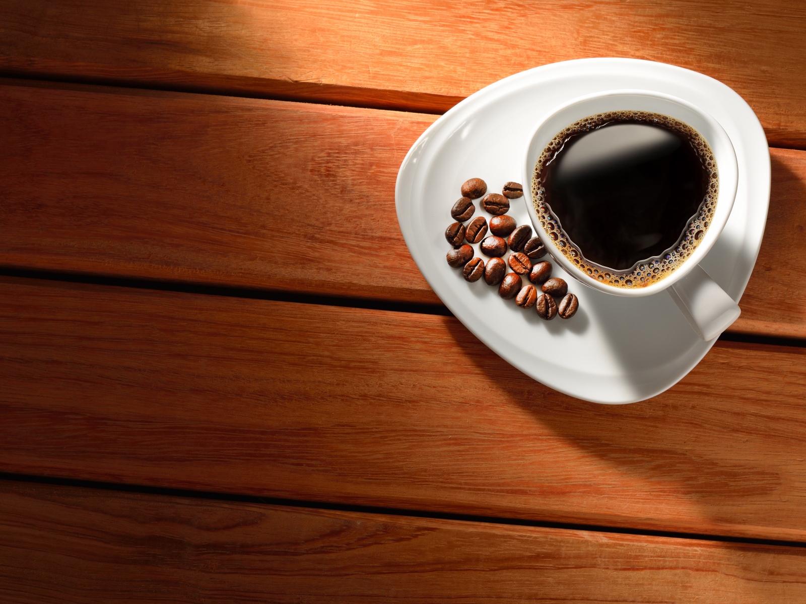 Чашка кофе на тарелке с зернами на деревянном столе