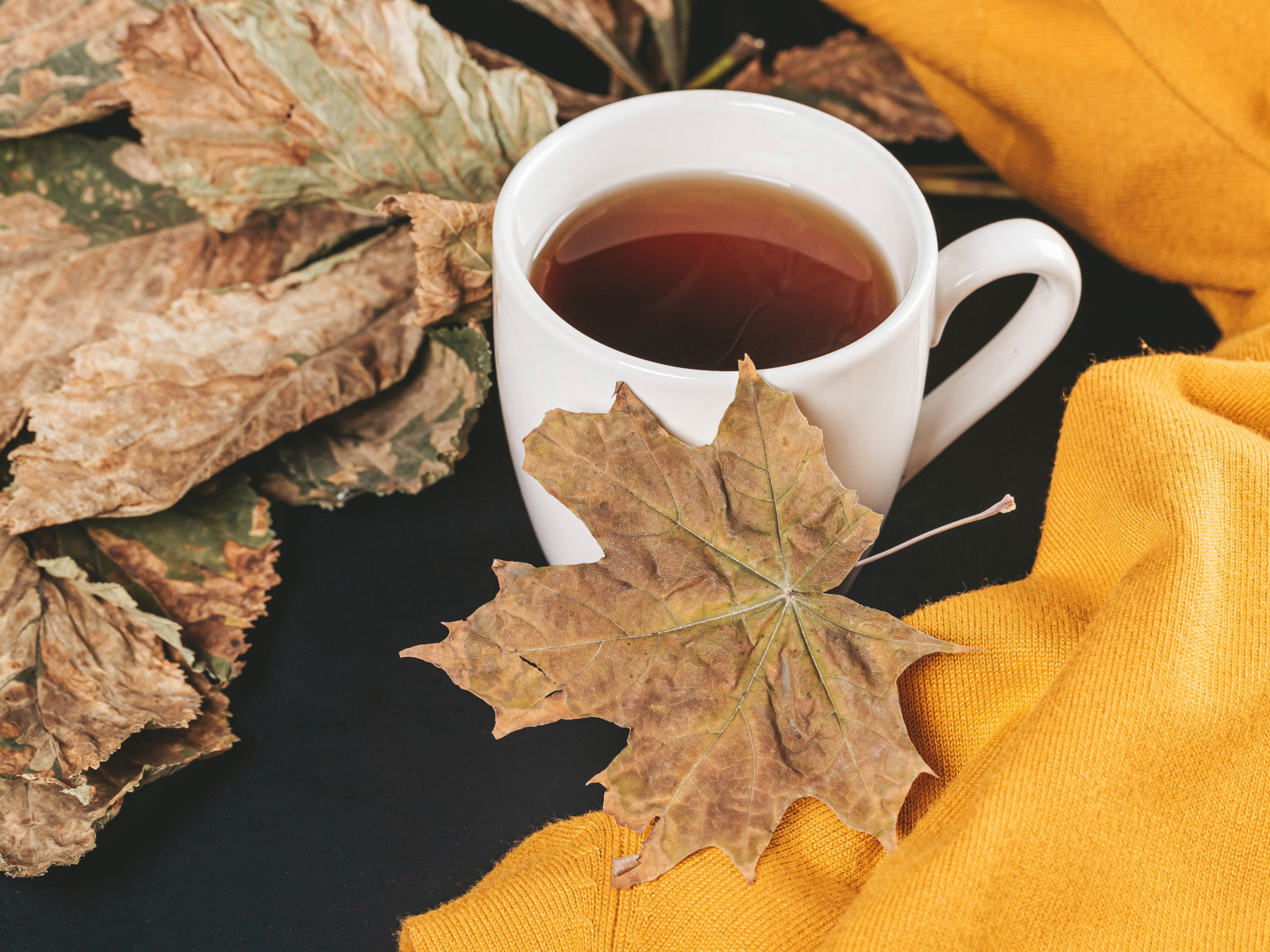 Чашка горячего чая на столе с сухими листьями