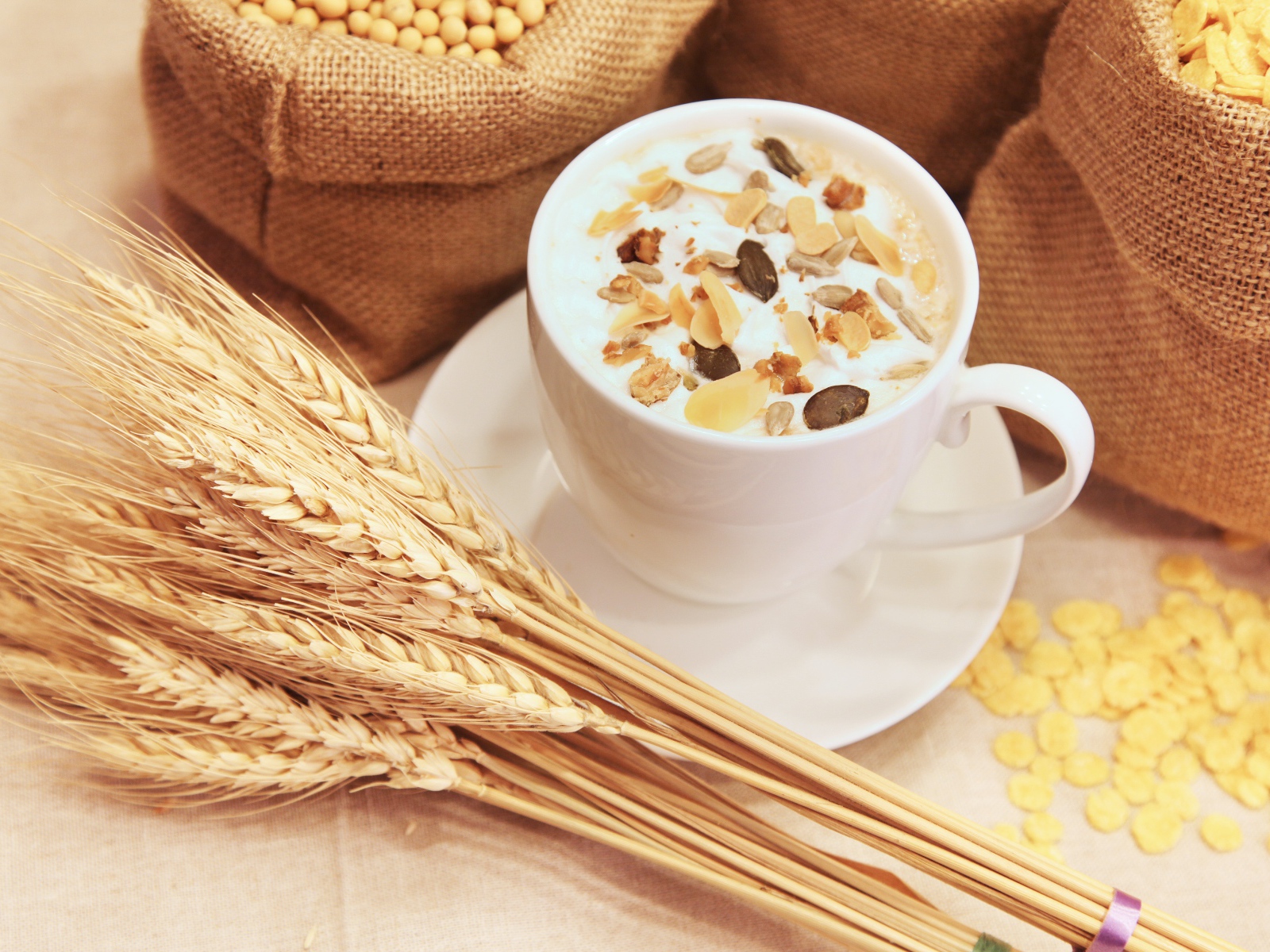 Чашка молока с мюсли на столе с колосками