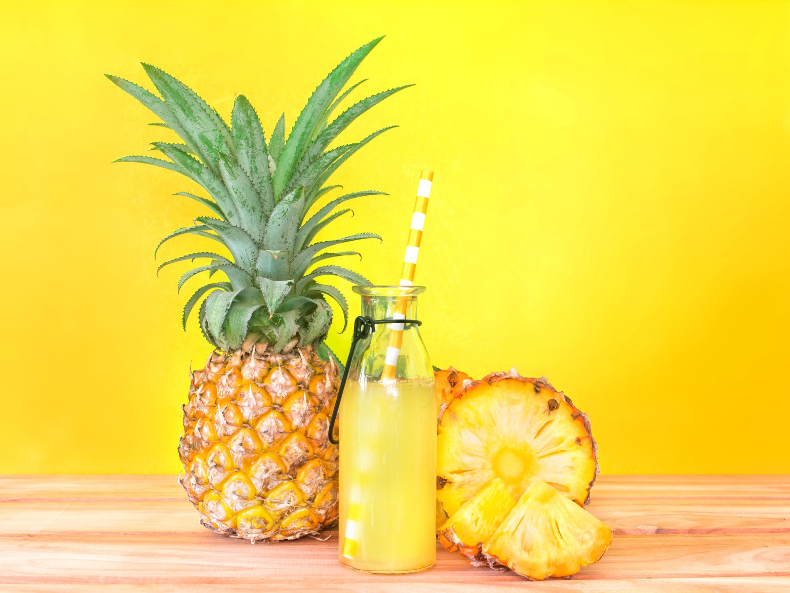 Сок в бутылке на столе с ананасами