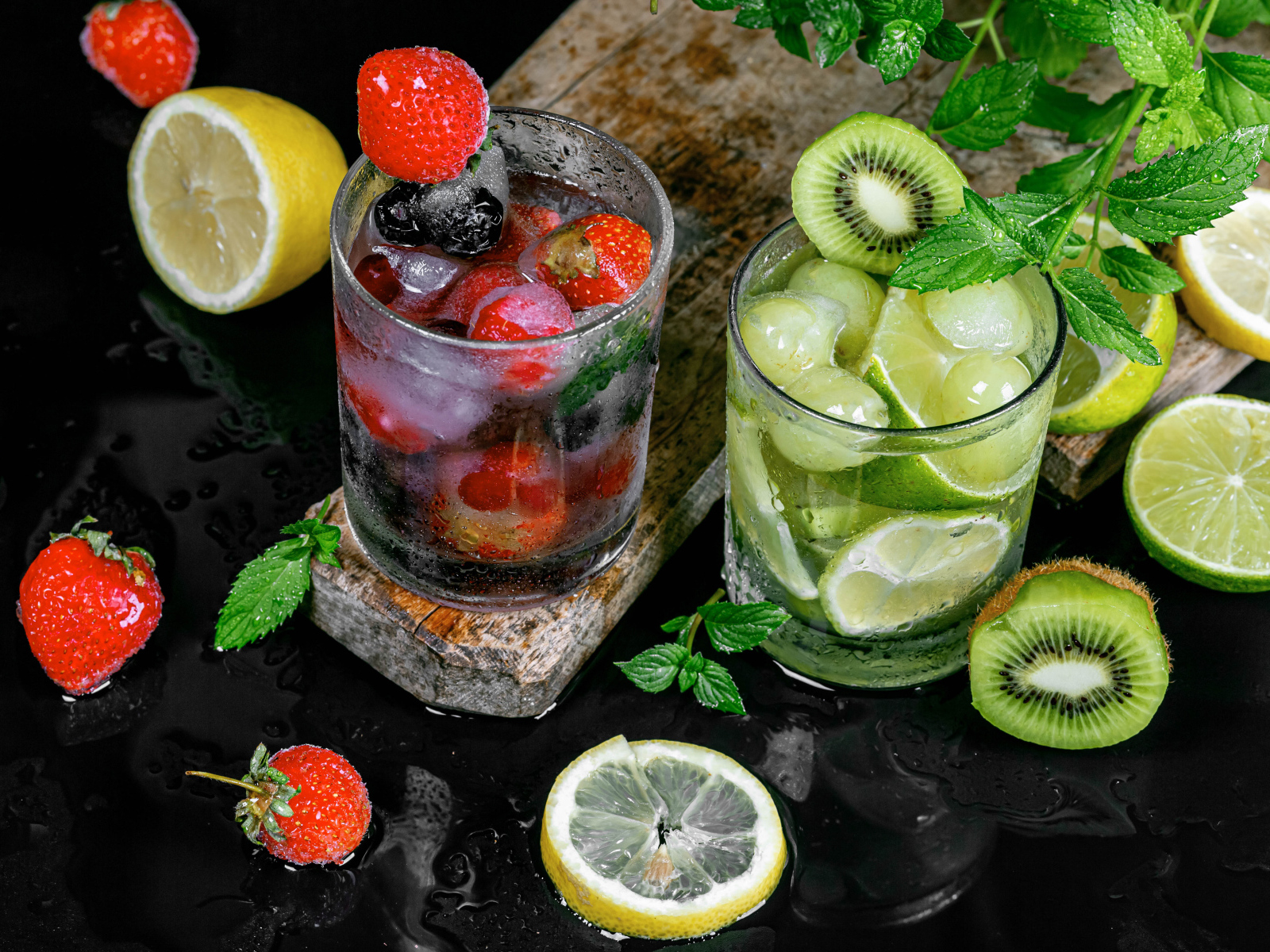 Два стакана мохито на столе с мятой, лимоном и клубникой 