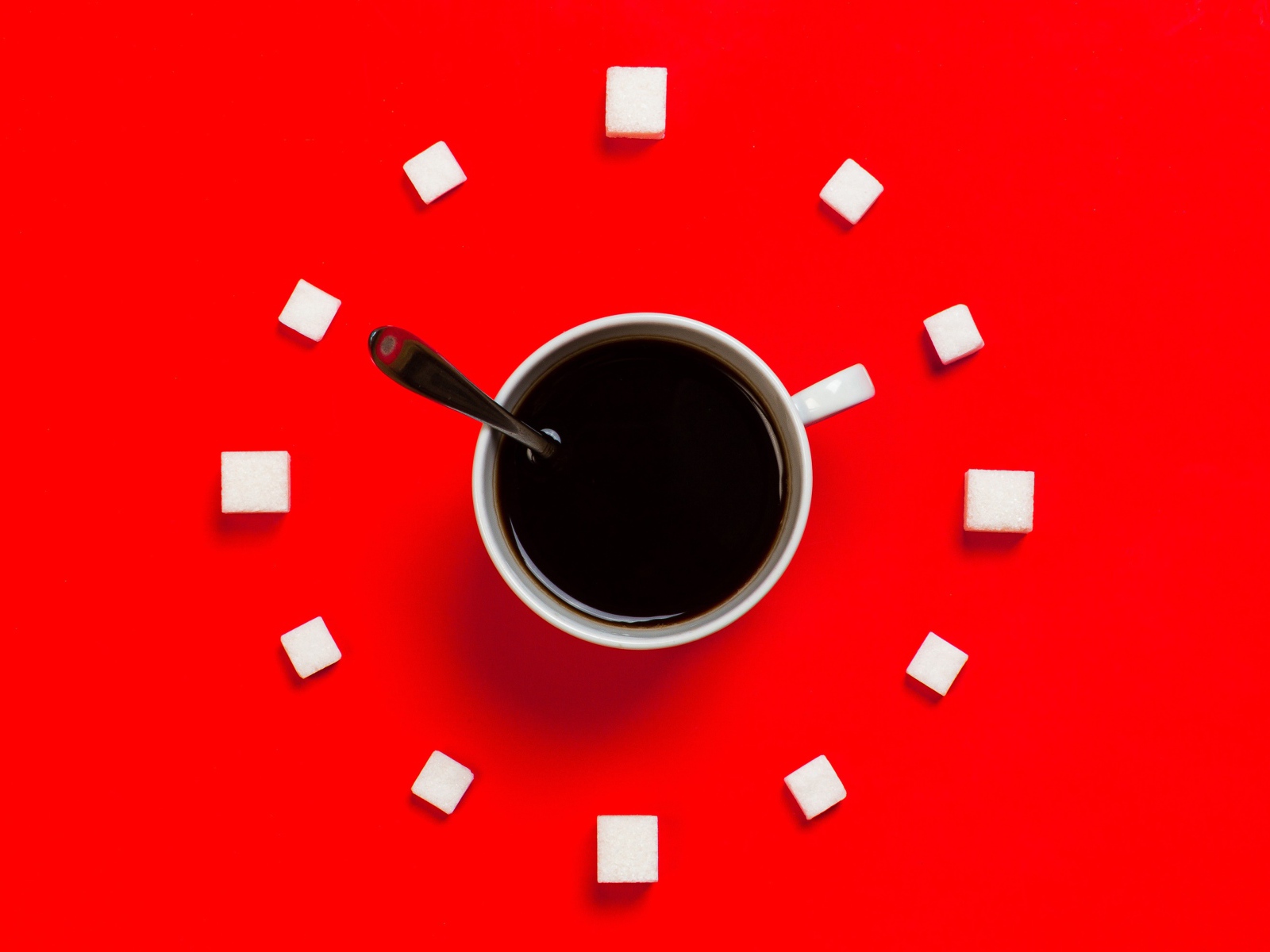 Белая чашка кофе на красном фоне с кубиками сахара 