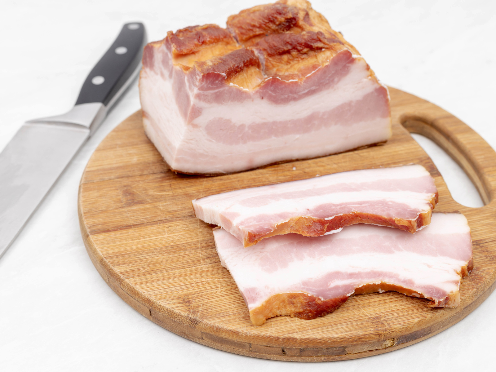 Кусок вкусного копченого сала на доске с ножом