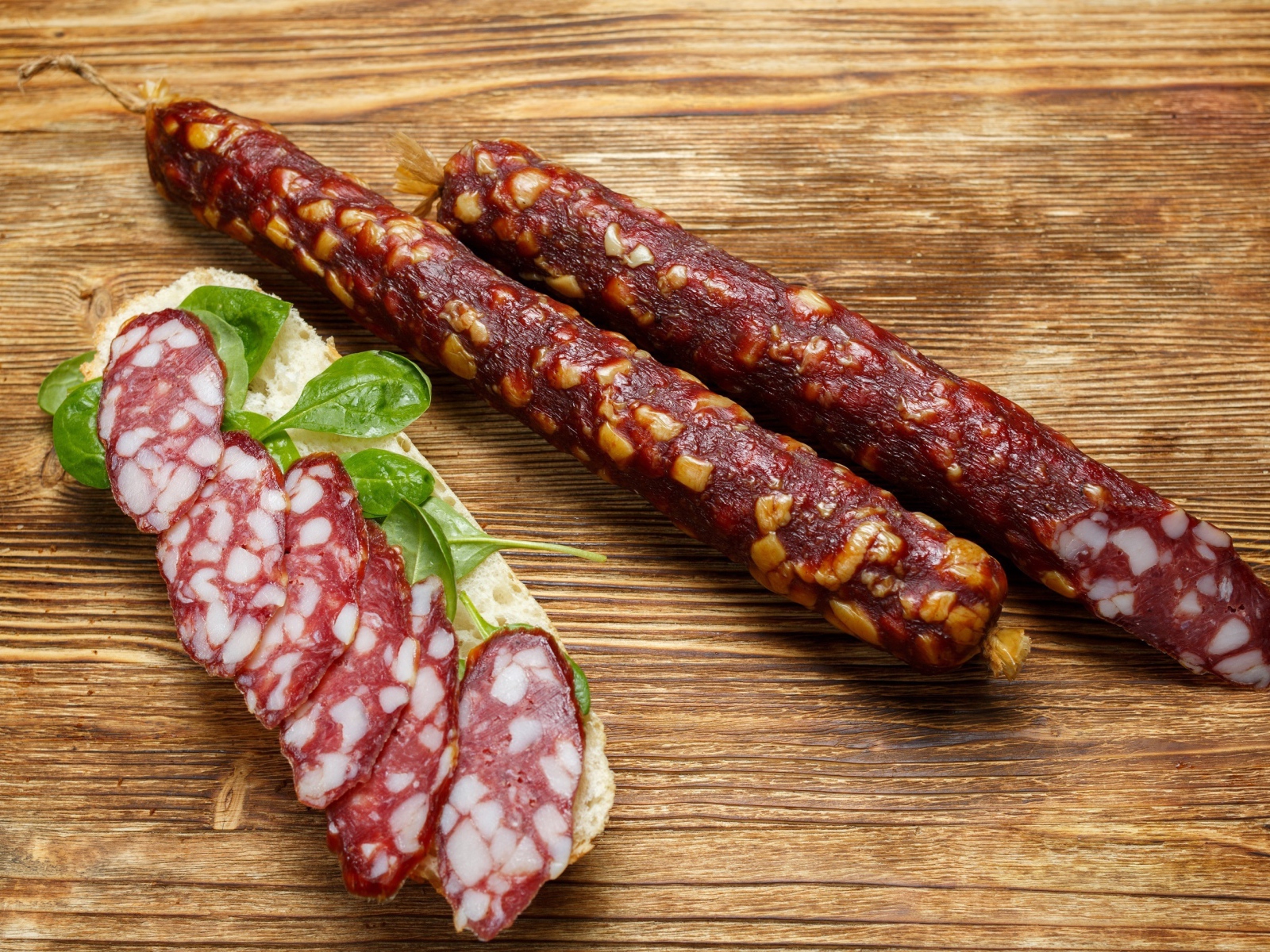 Вкусная сухая колбаса на столе с бутербродом