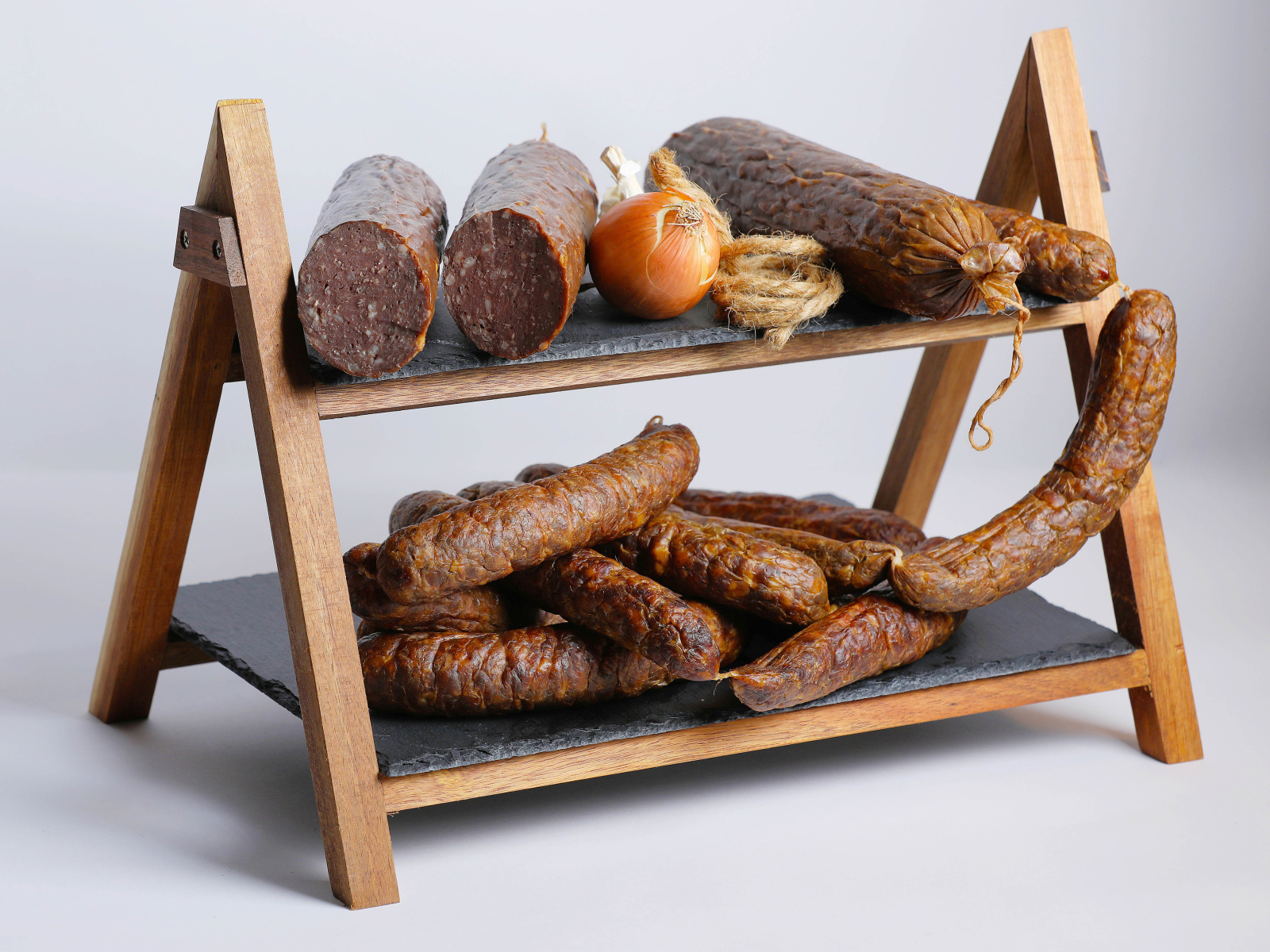 Различные виды колбасы на полке с луком на сером фоне