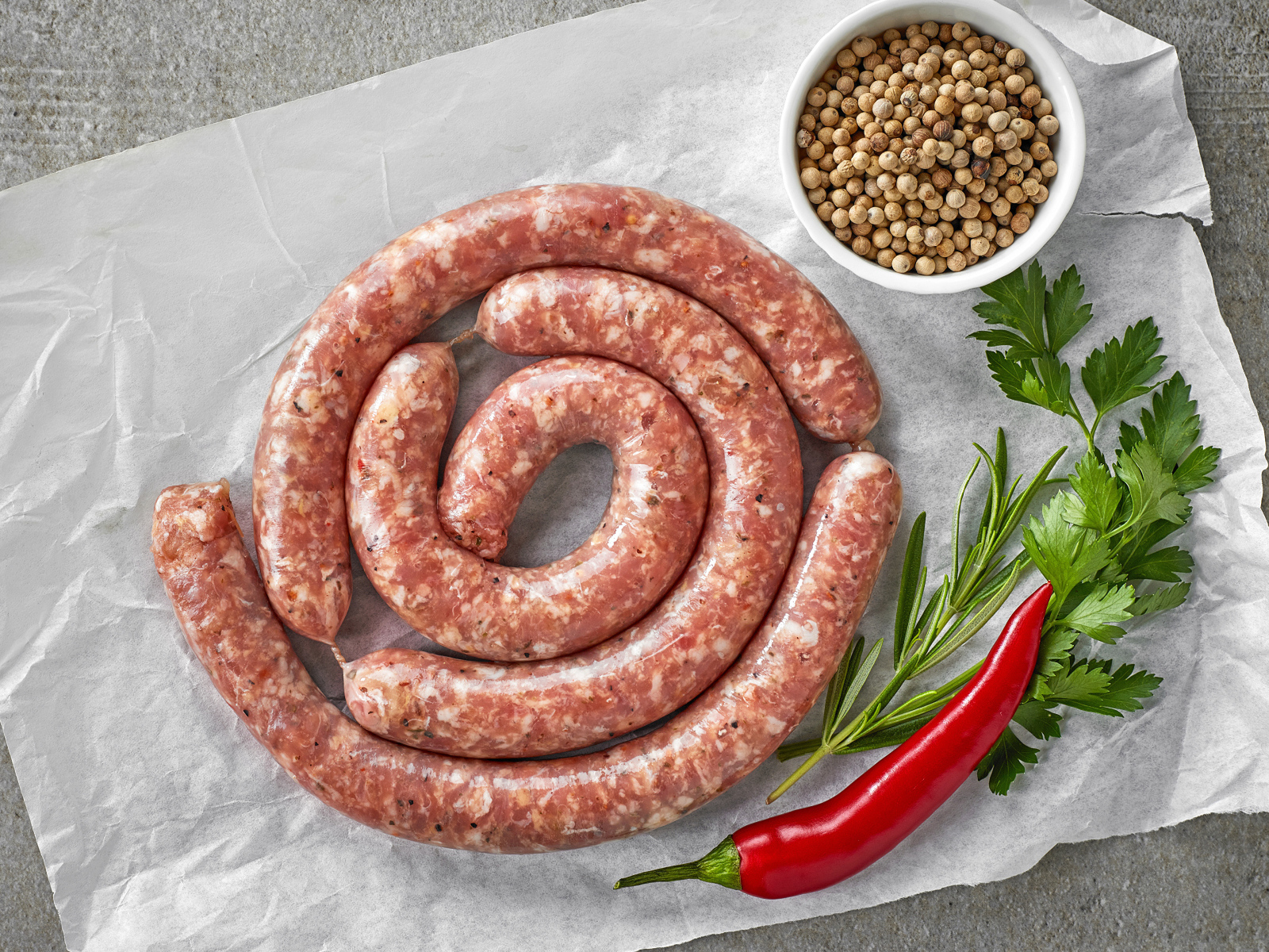 Домашняя колбаса на столе с зеленью и перцем