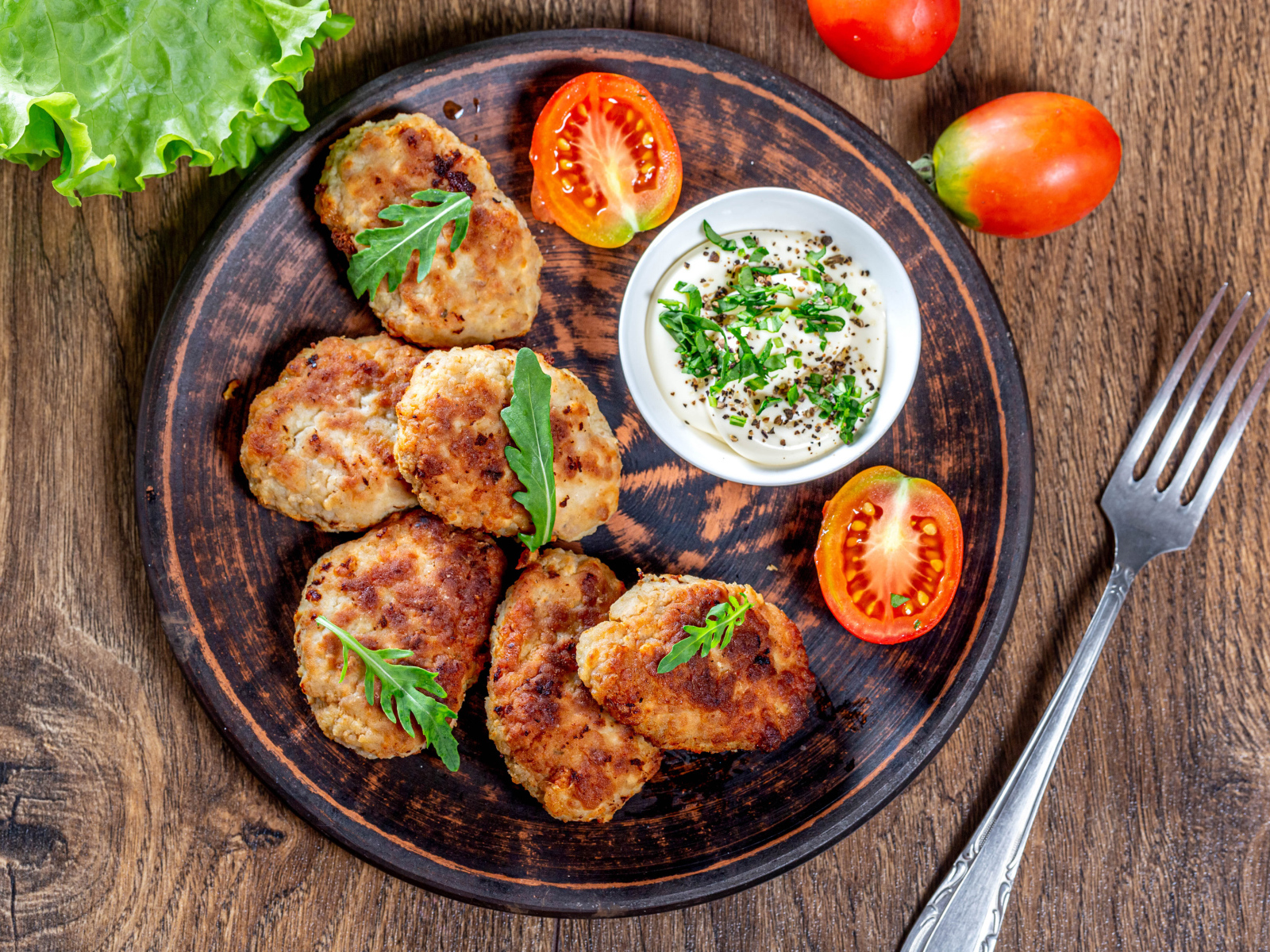 Вкусные котлеты на столе с соусом и помидорами