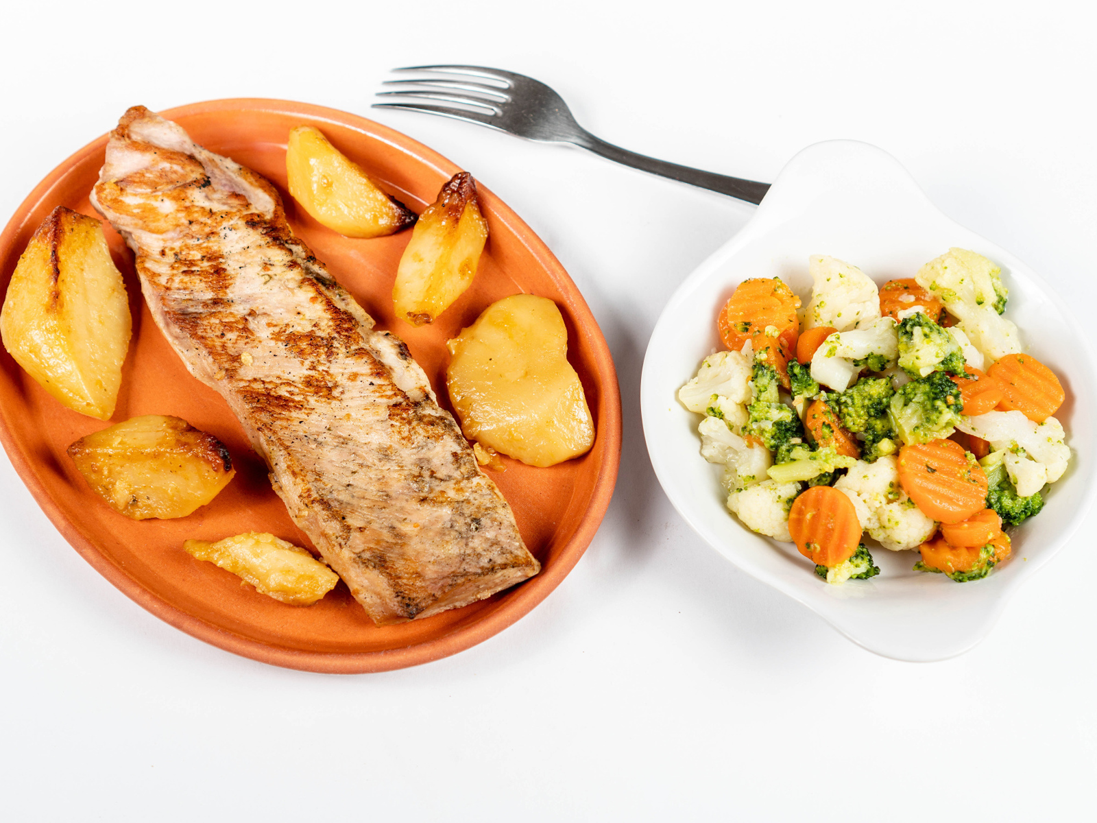 Кусок запеченной рыбы на тарелке с овощами 