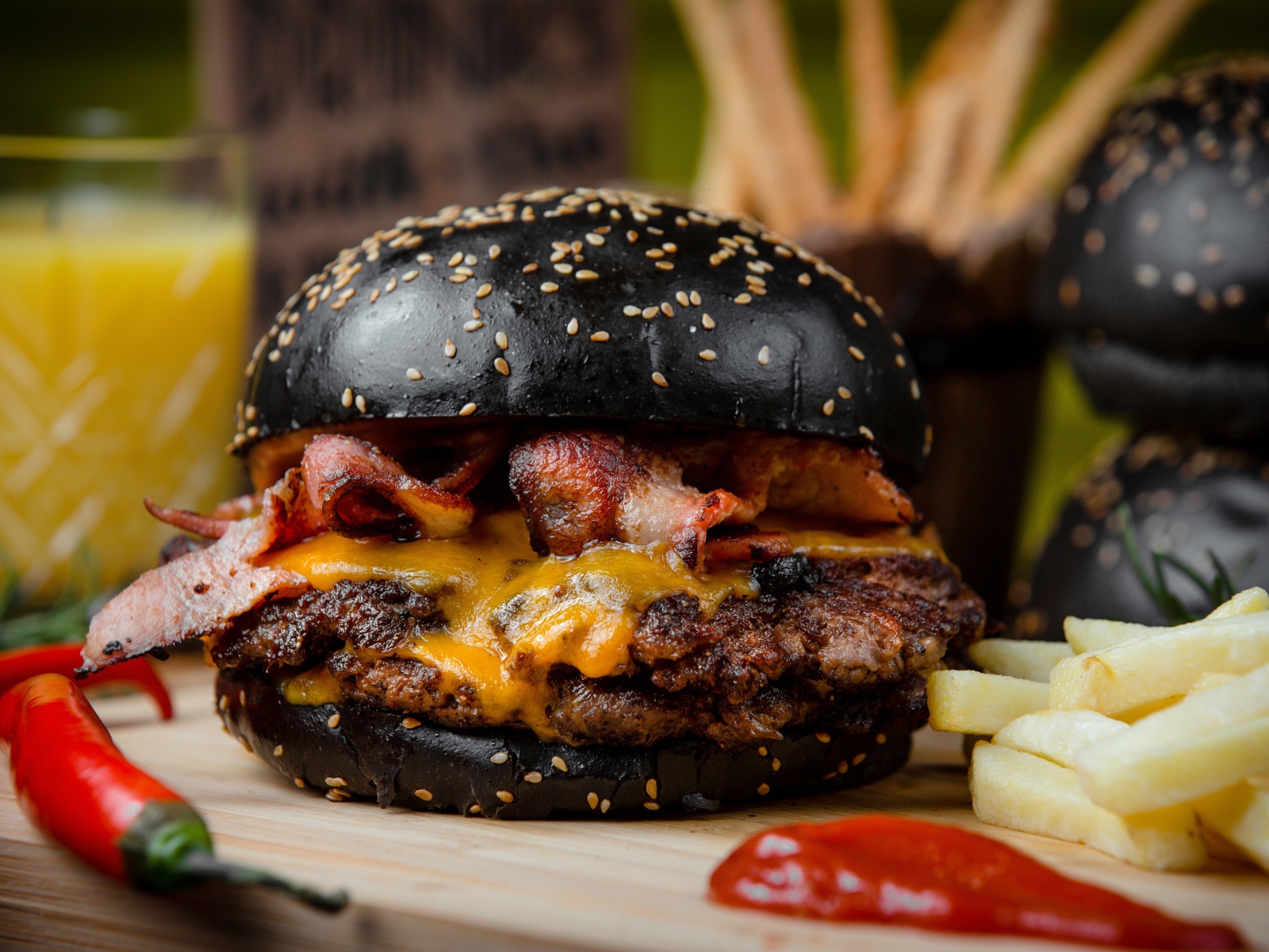 Гамбургер с черной булкой на столе с картофелем фри и красным перцем