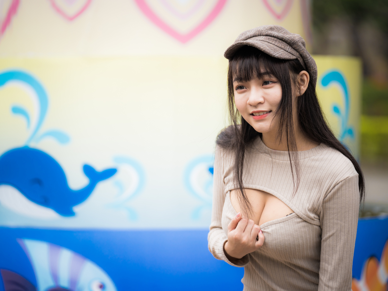 Улыбающаяся девушка азиатка стоит у стены  с рисунком