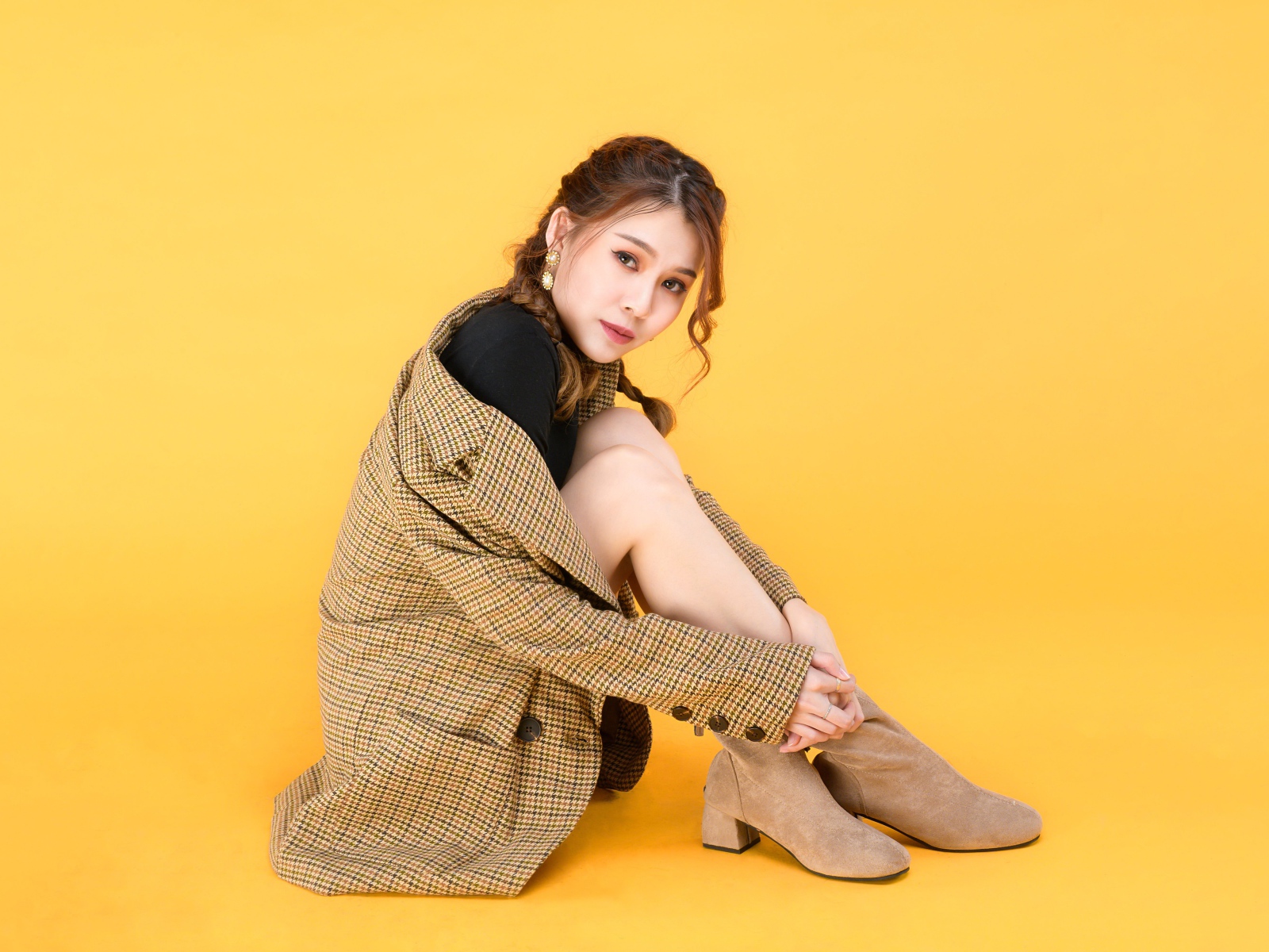 Девушка азиатка в пальто на желтом фоне 