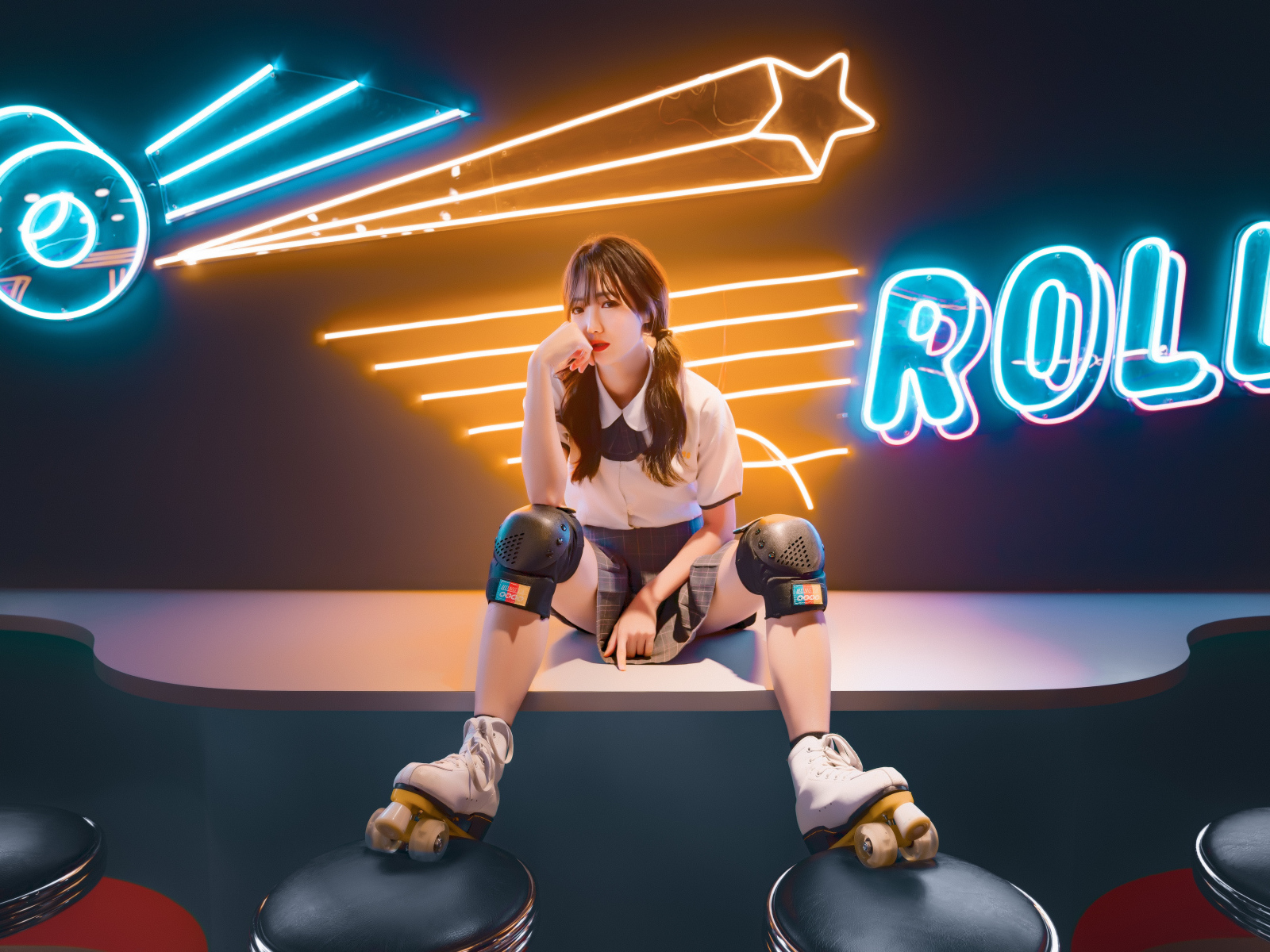 Девушка азиатка сидит в роликах на фоне вывески 