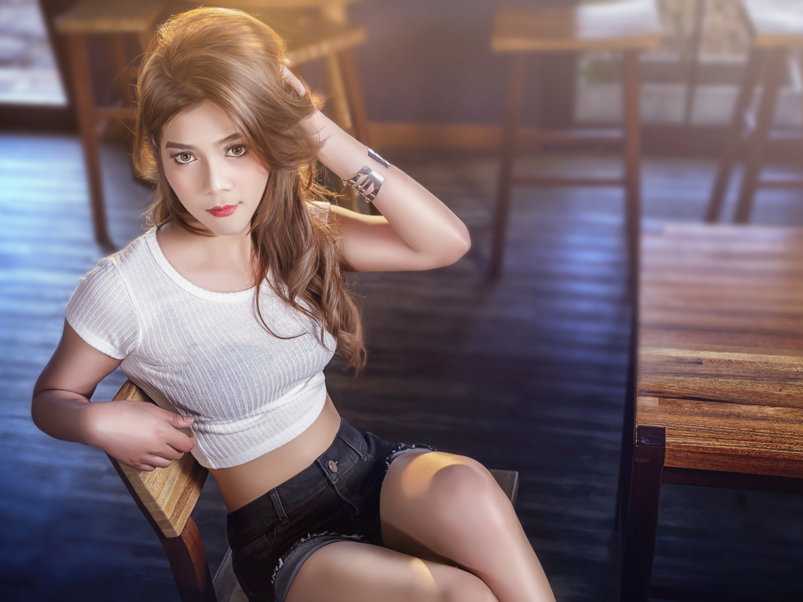 Девушка азиатка сидит на деревянном стуле в кафе