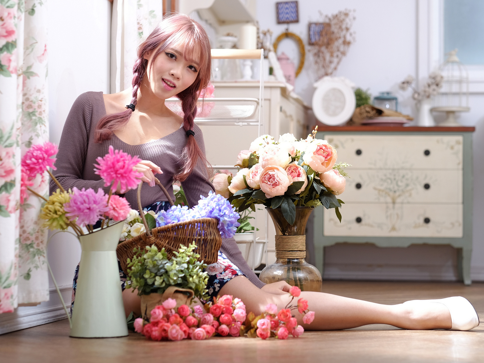 Девушка азиатка сидит с цветами на полу у окна