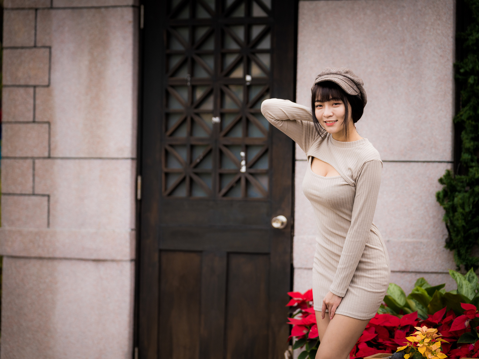 Красивая азиатка в платье стоит у двери 