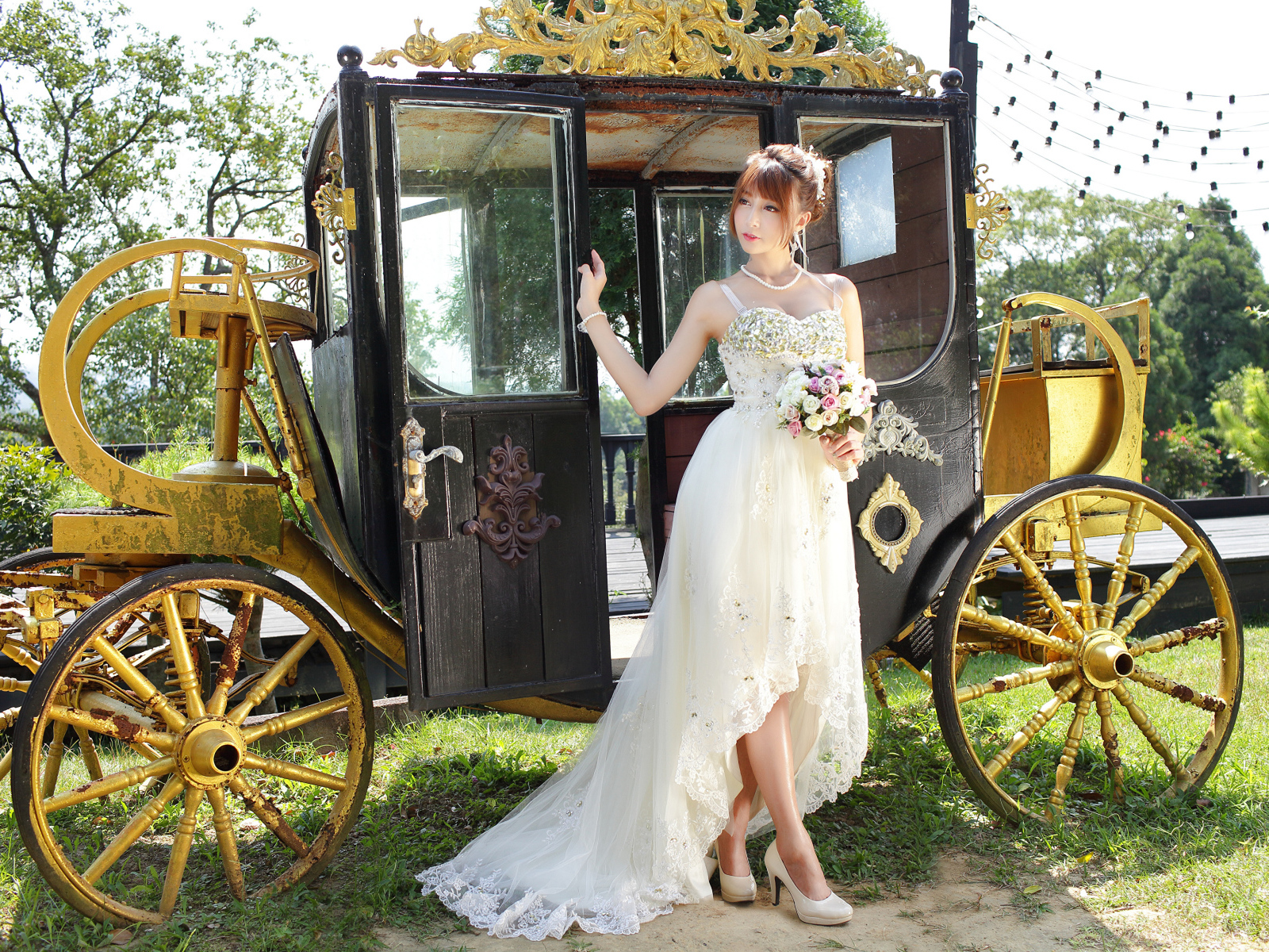 Красивая девушка азиатка в свадебном платье у кареты 