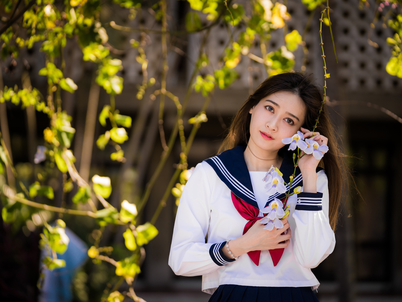 Красивая девушка азиатка в форме с цветами в руках 