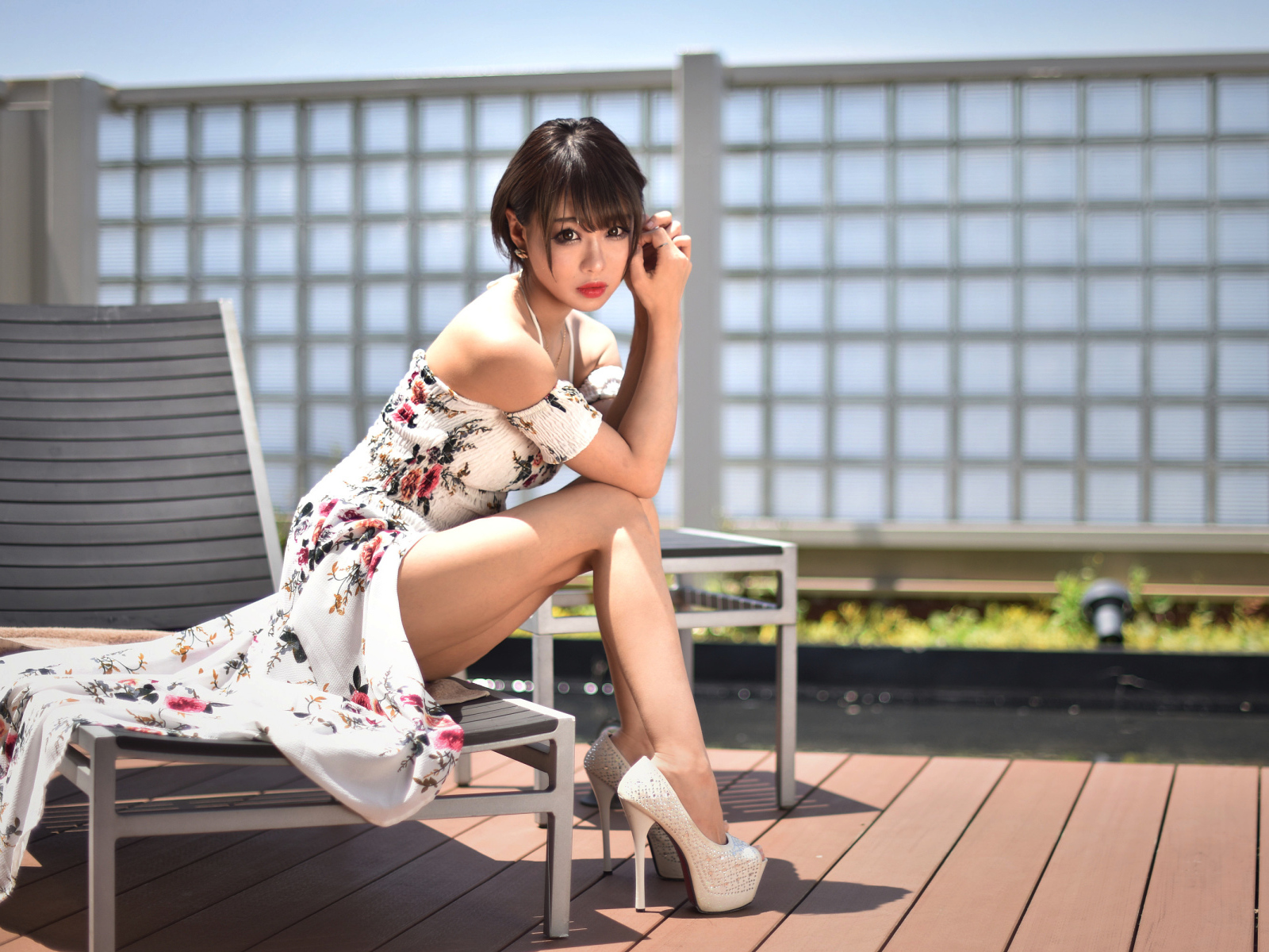 Красивая девушка азиатка сидит на шезлонге 