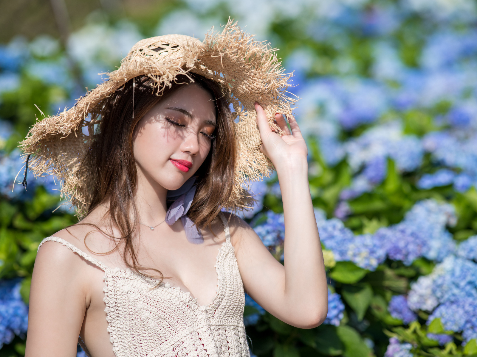 Красивая девушка азиатка с закрытыми глазами на фоне цветов гортензии