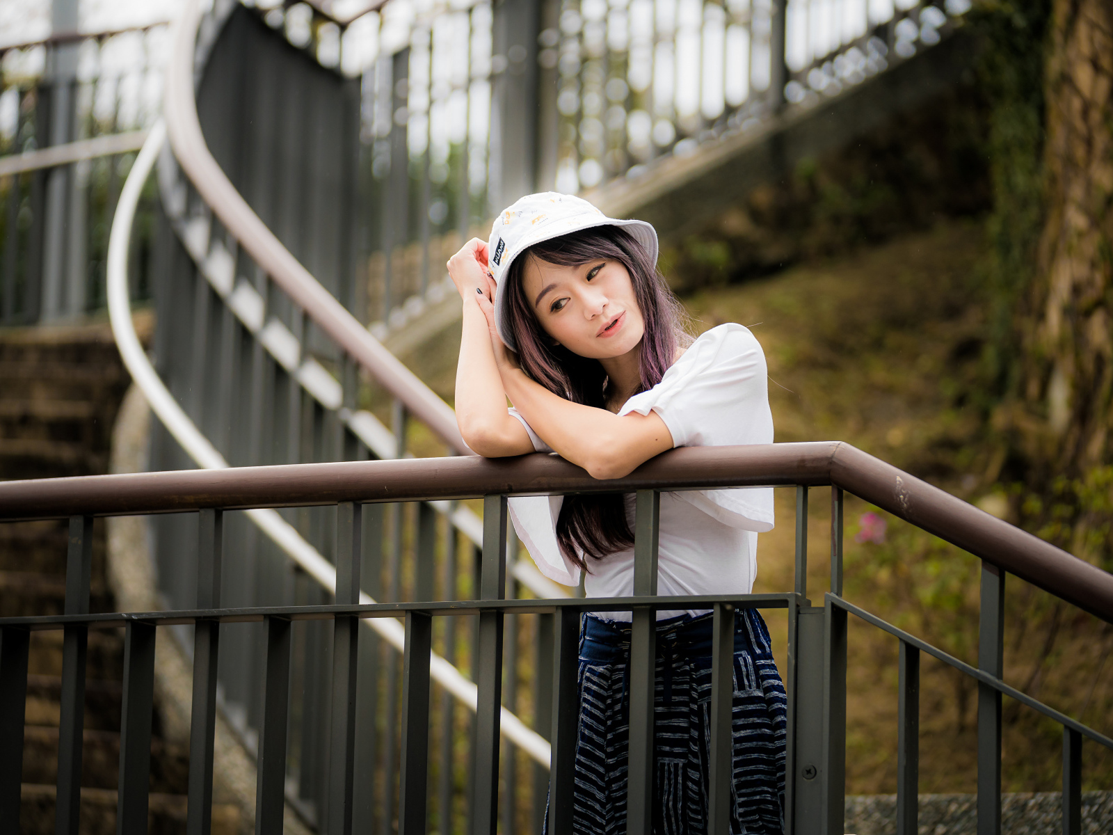 Красивая азиатка в панаме стоит у перил