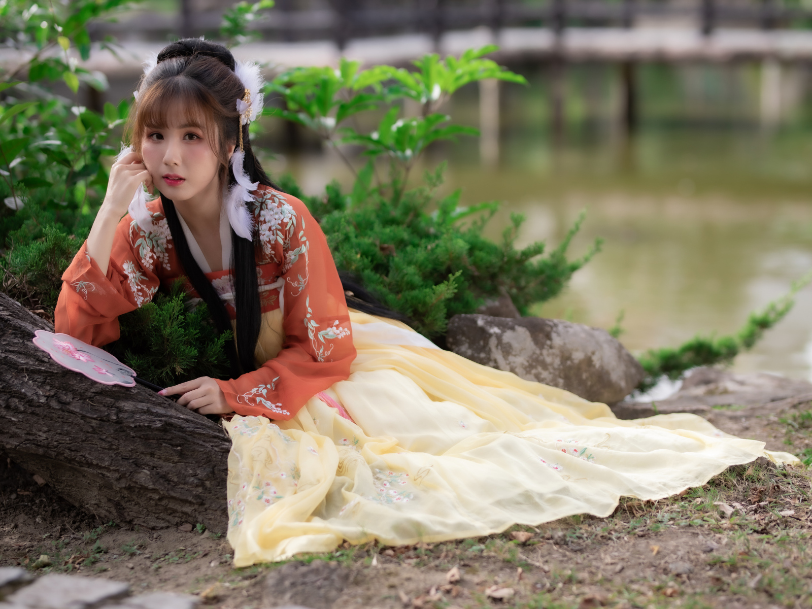 Красивая девушка азиатка сидит на земле у дерева 