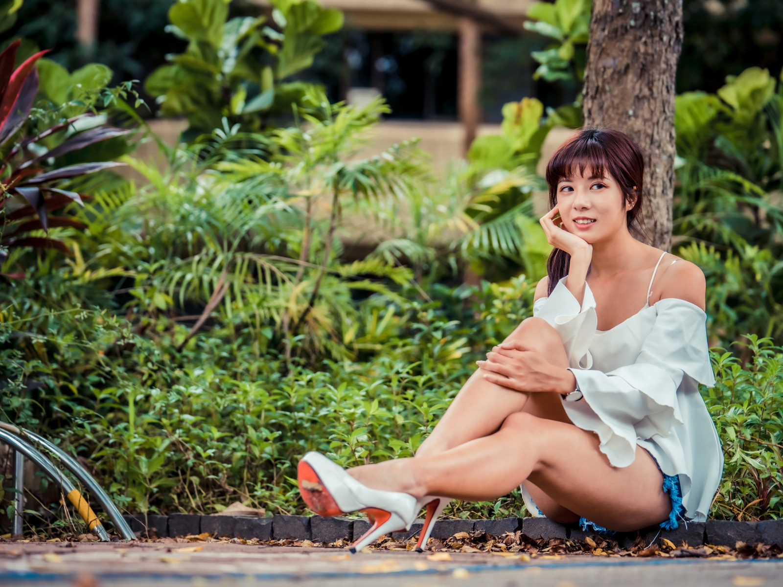 Красивая девушка азиатка сидит на земле в парке 