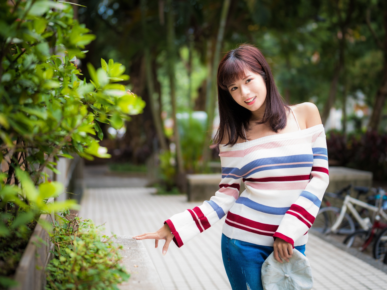 Красивая азиатка в полосатом свитере в парке