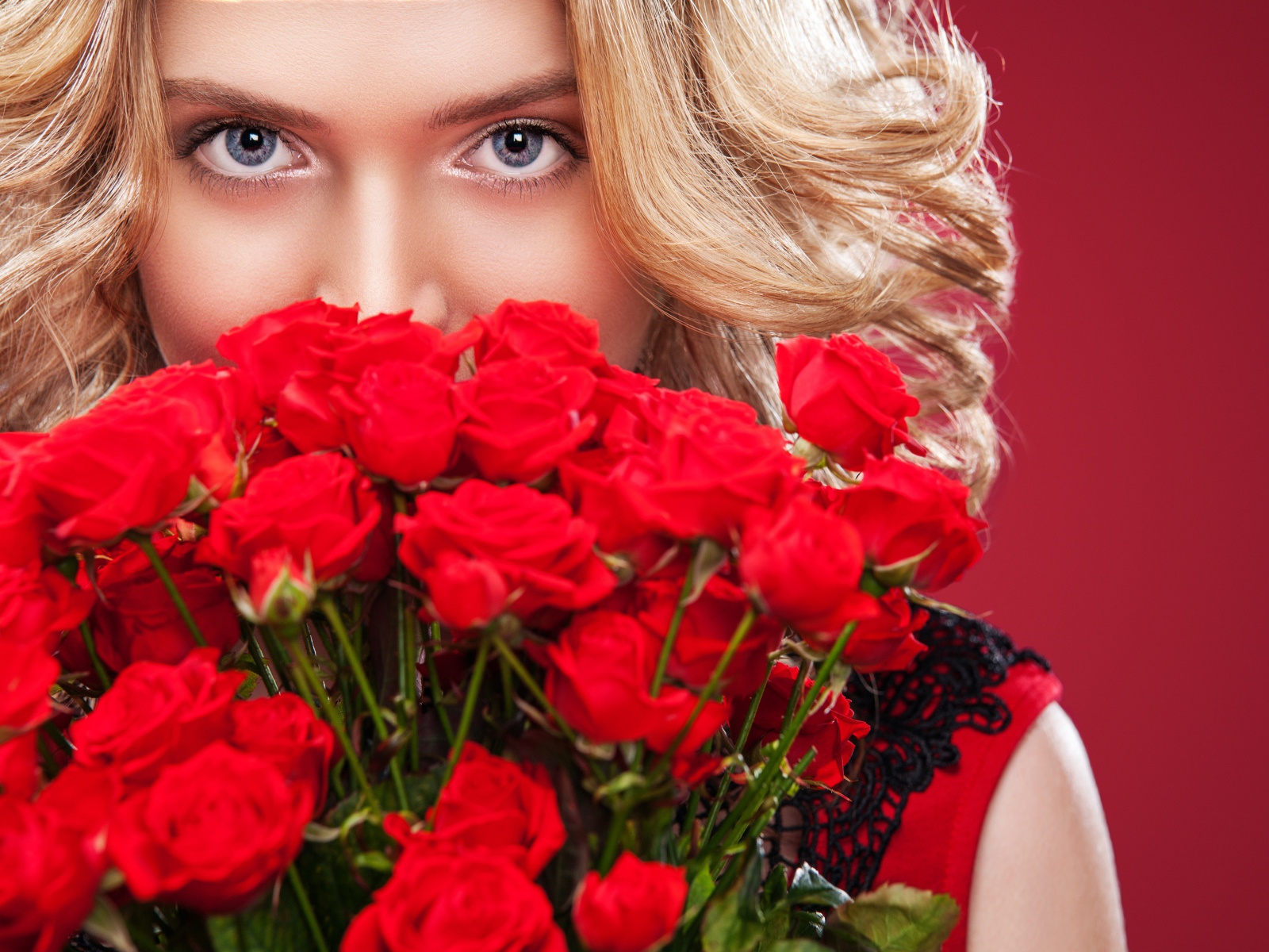 Красивая голубоглазая блондинка с букетом красных роз 