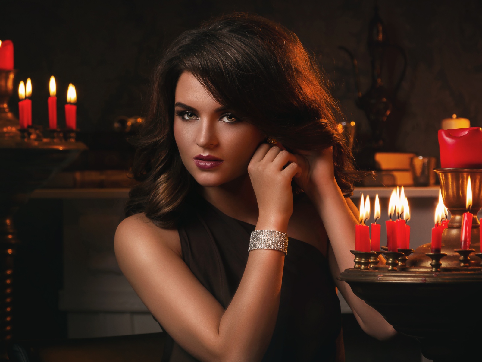 Красивая брюнетка в черном платье и зажженными свечами