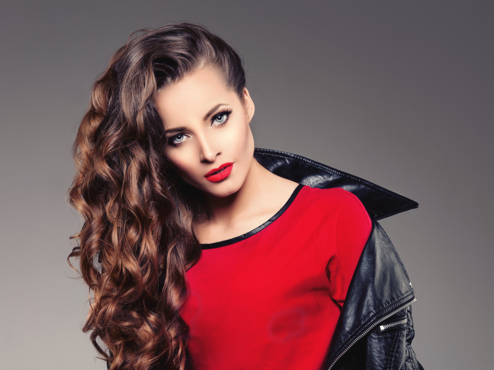 Красивая девушка в черной кожаной куртке и красном свитере