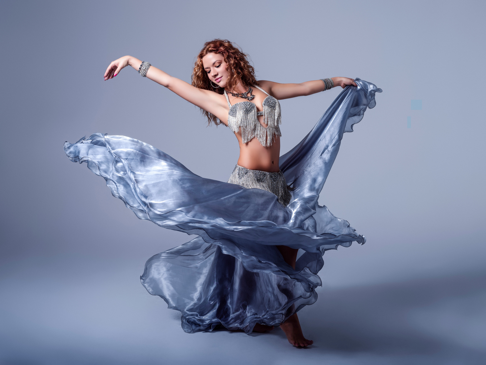 Красивая девушка в платье для танцев на сером фоне
