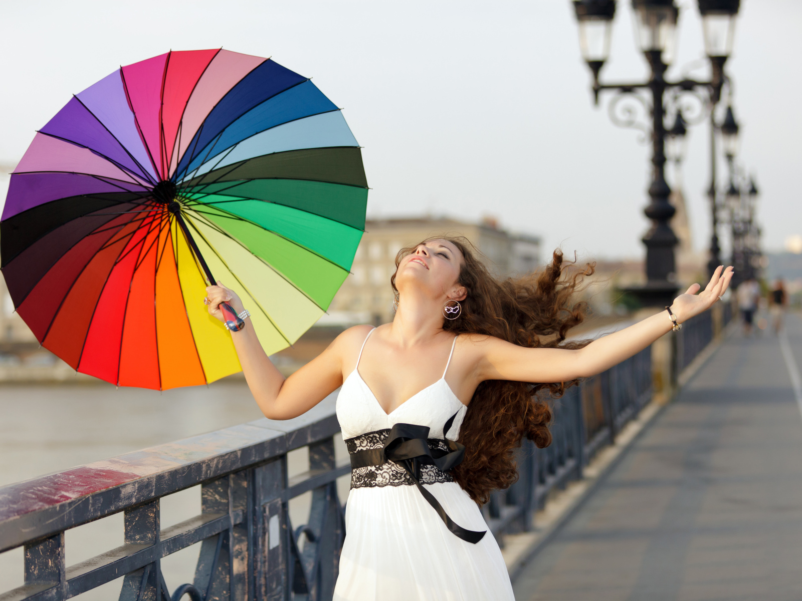 Красивая девушка идет по мосту с разноцветным зонтом