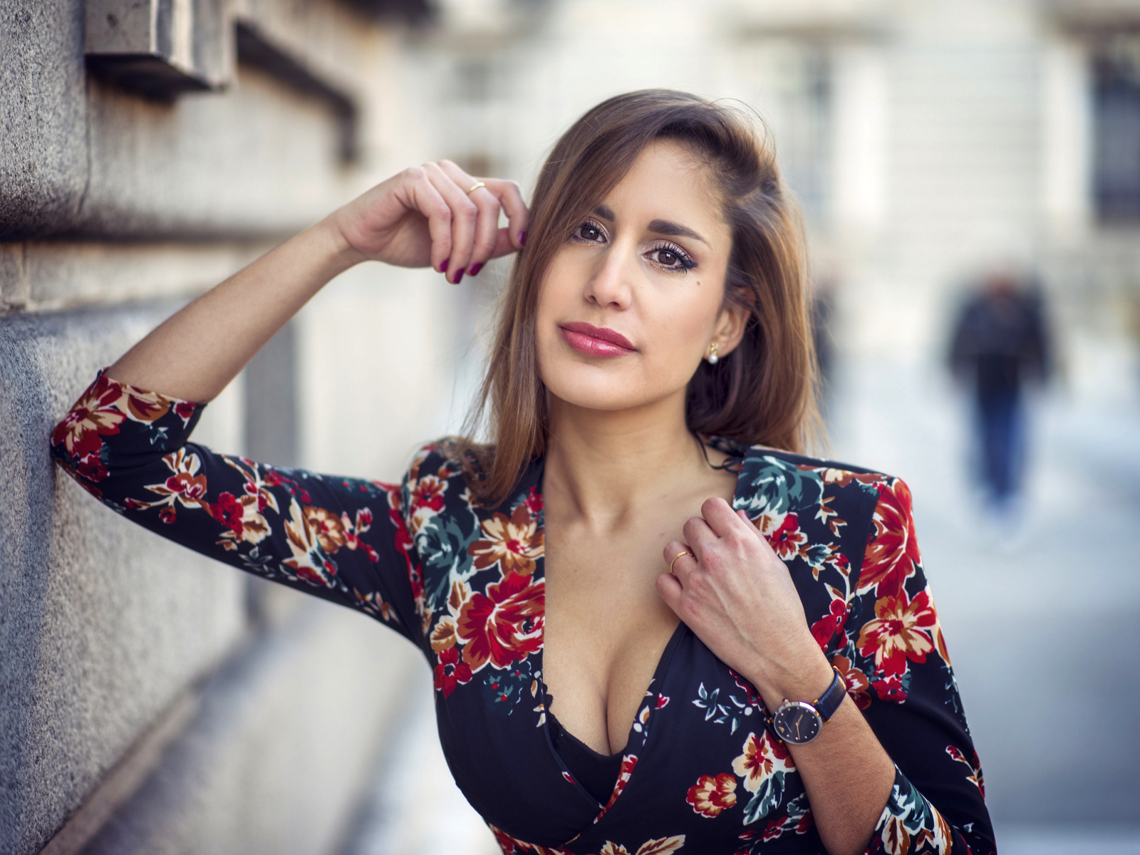 Красивая девушка с часами на руке стоит у стены