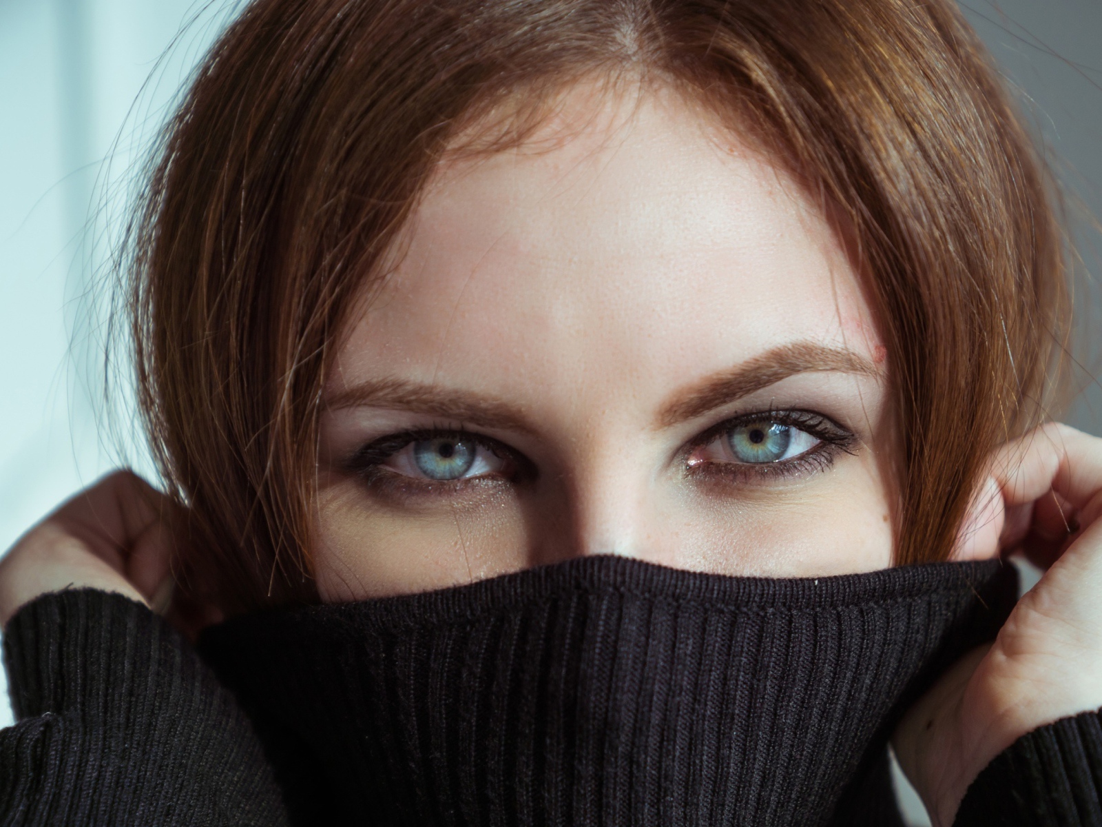 Красивая девушка с голубыми глазами закрыла лицо свитером 