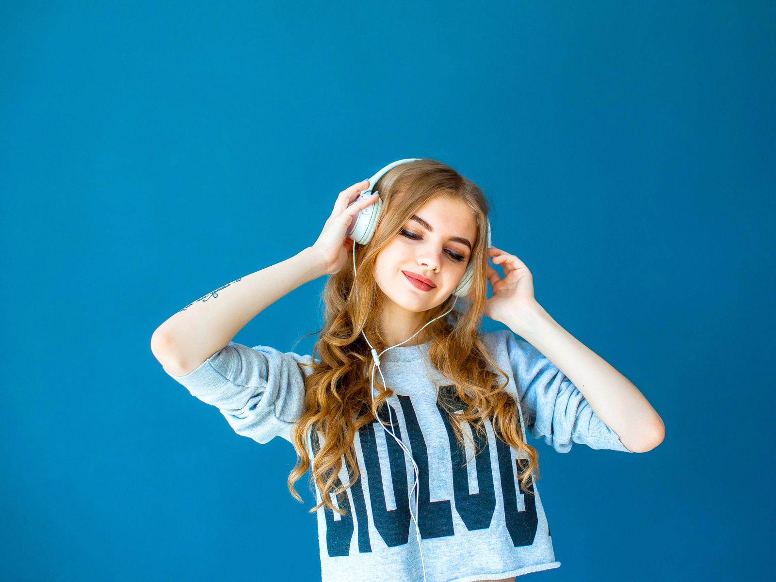 Красивая молодая девушка в наушниках на голубом фоне
