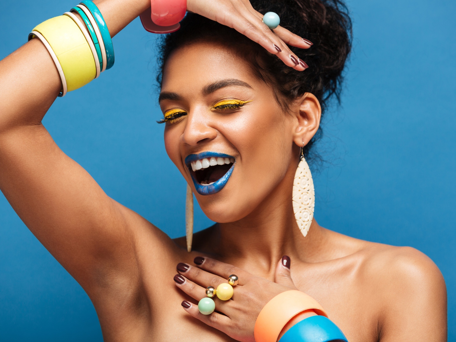 Красивая молодая девушка с ярким разноцветным макияжем на голубом фоне